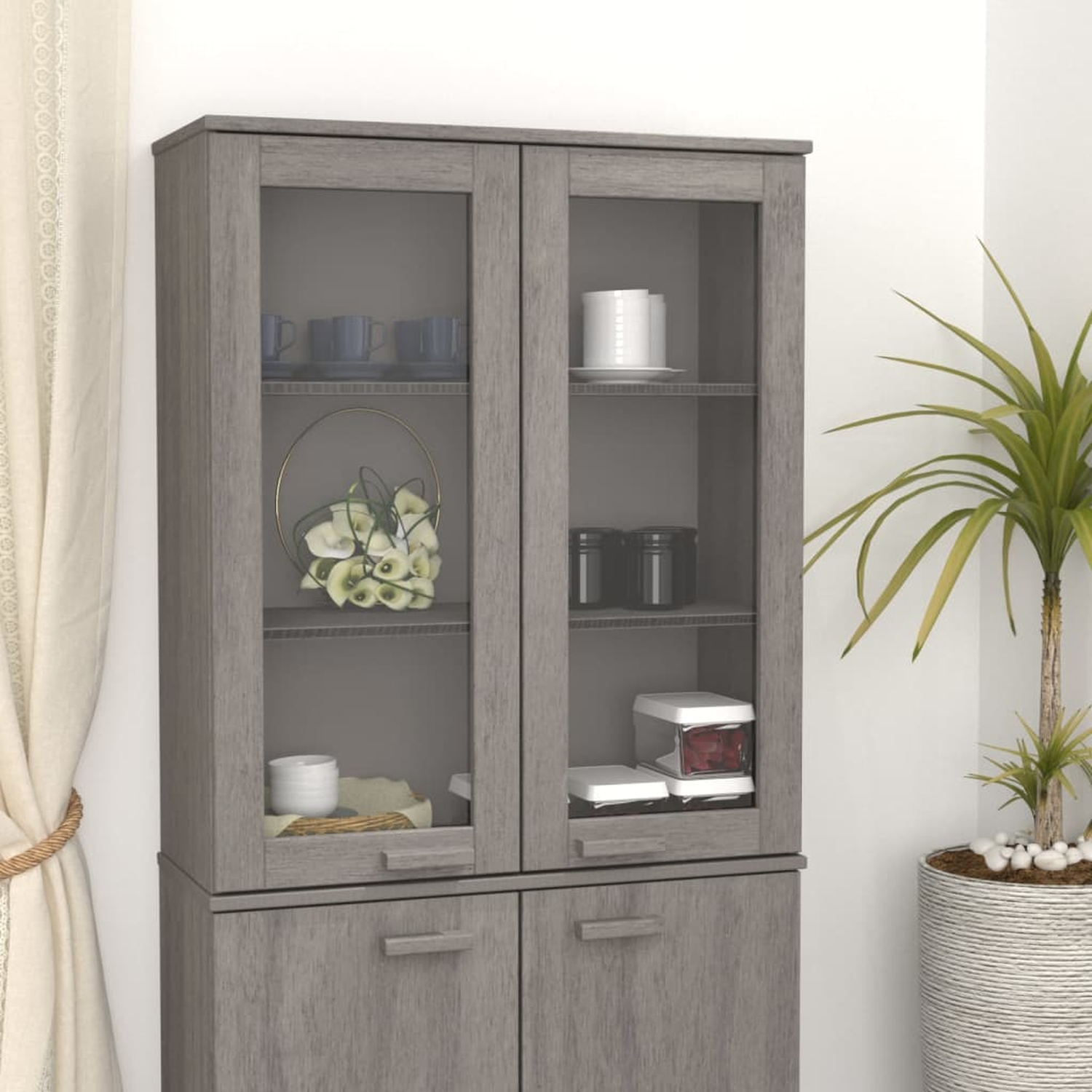 Ein grauer Schrank mit Glastüren, der Dekor und Geschirr zeigt, in einer häuslichen Umgebung.