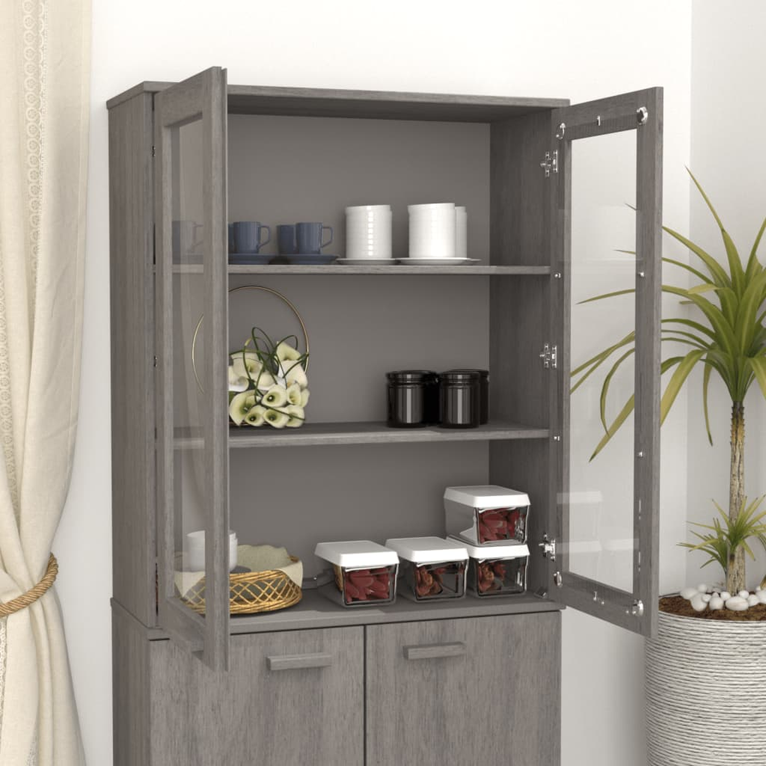 Ein grauer Schrank mit Glastüren, der Regale mit Gegenständen zeigt, und eine Pflanze im Topf.