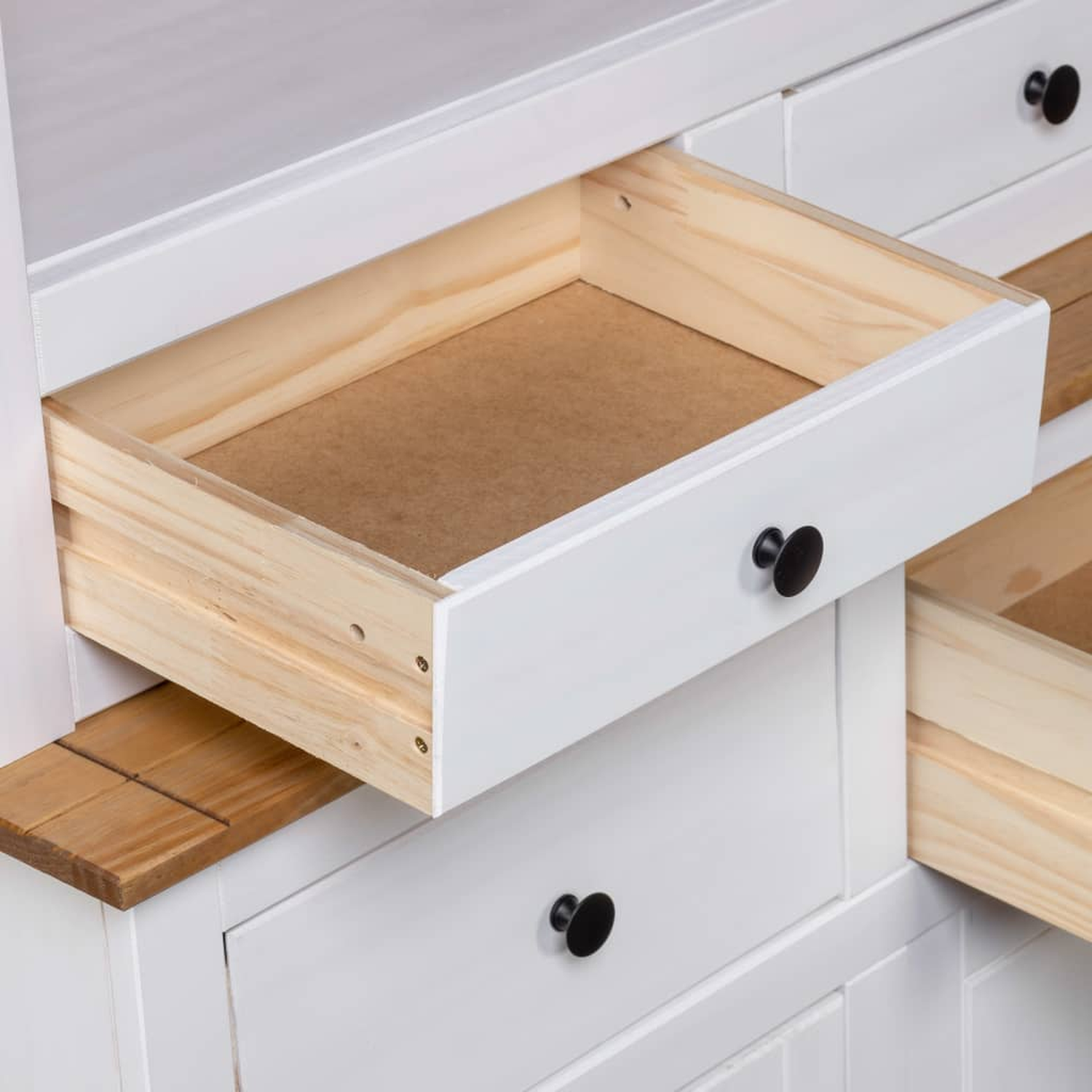 Weißer Schrank mit geöffneter Schublade, Innenansicht. Schwarze Knöpfe.