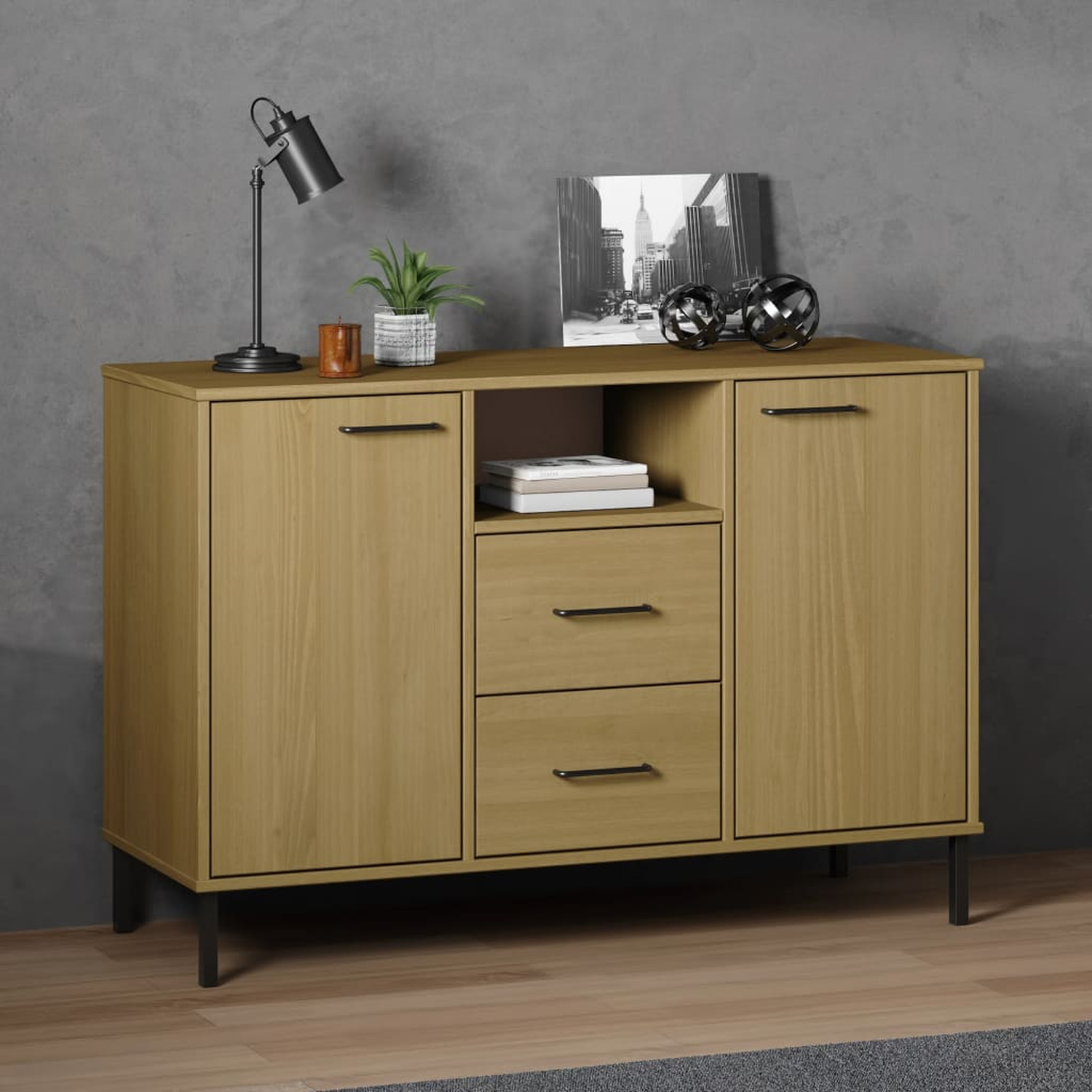 Holzschrank mit zwei Türen und Schubladen. Lampe, Pflanze und Deko oben. Graue Wand.