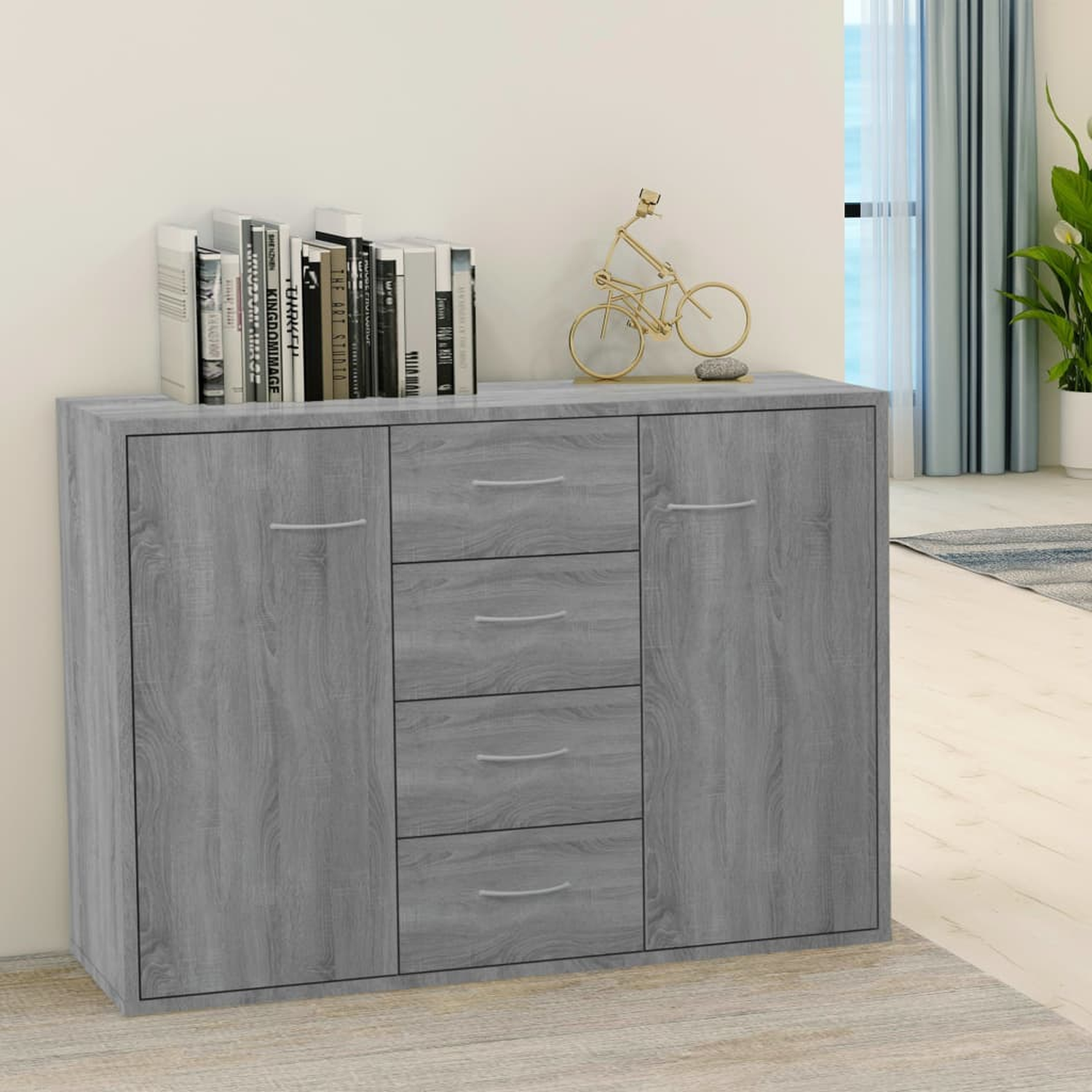 Grauer Schrank mit Türen und Schubladen. Bücher, Fahrradschmuck und Deko oben.