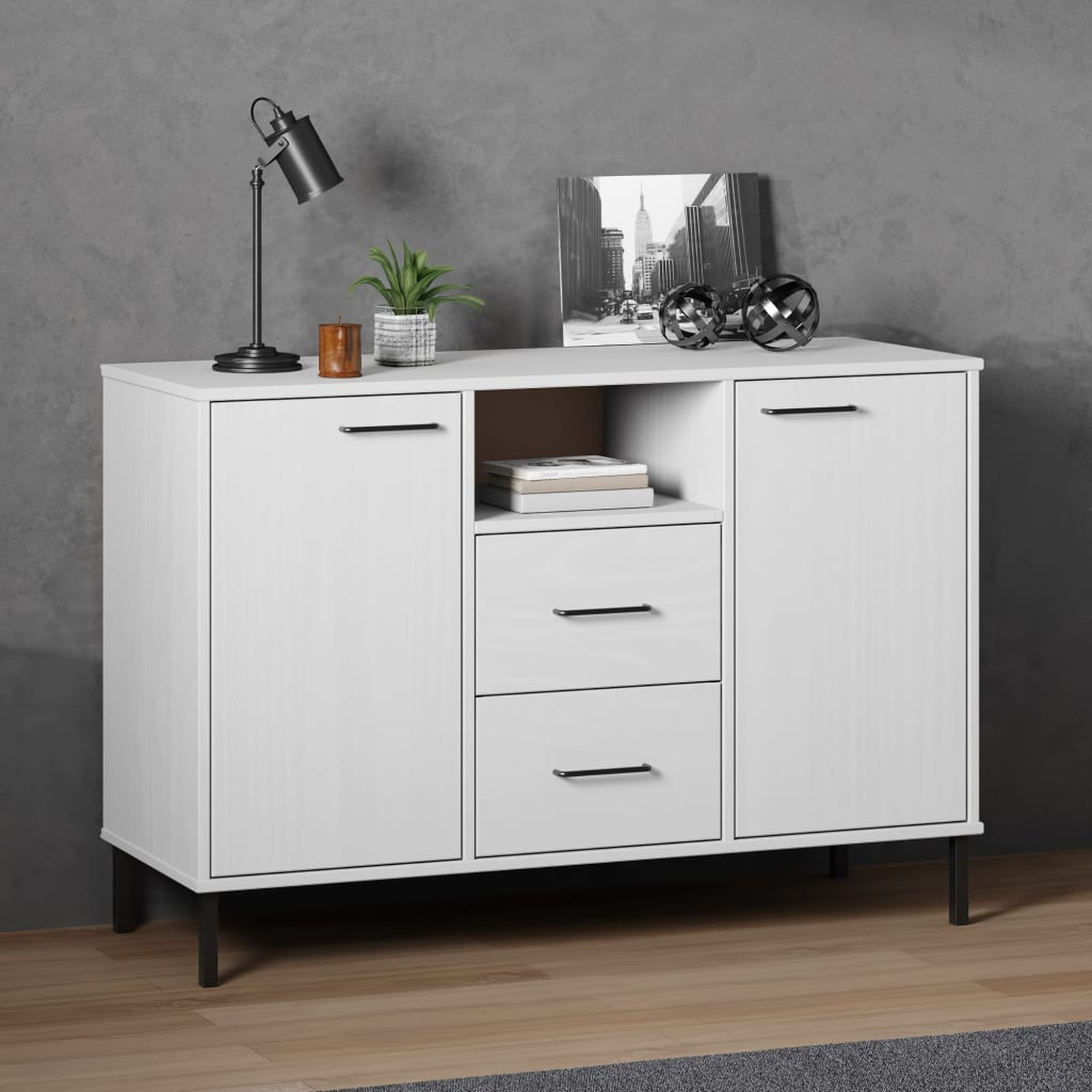 Weißes Sideboard mit schwarzen Griffen und Beinen. Enthält Schubladen und offenes Regal. Graue Wand und Holzboden.