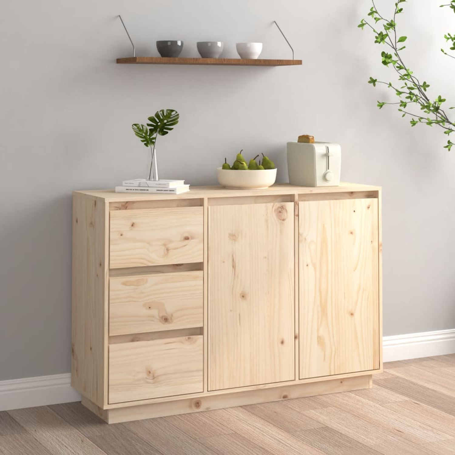 Holzschrank mit drei Schubladen und zwei Türen. Es gibt einen Toaster, Birnen und eine Pflanze.