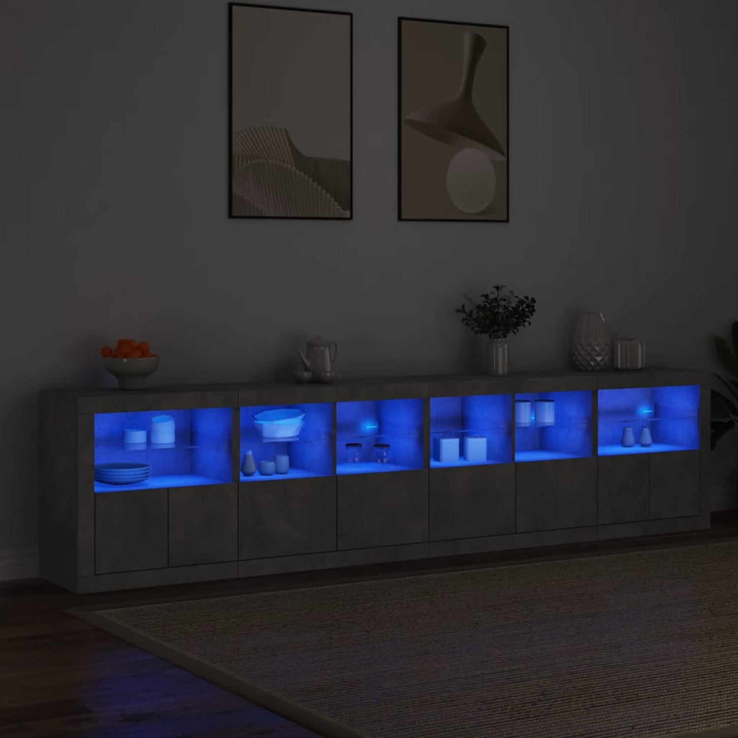 Ein grauer Schrank mit blauen Lichtern im Inneren. Er hat Gegenstände oben drauf und zwei gerahmte Bilder.