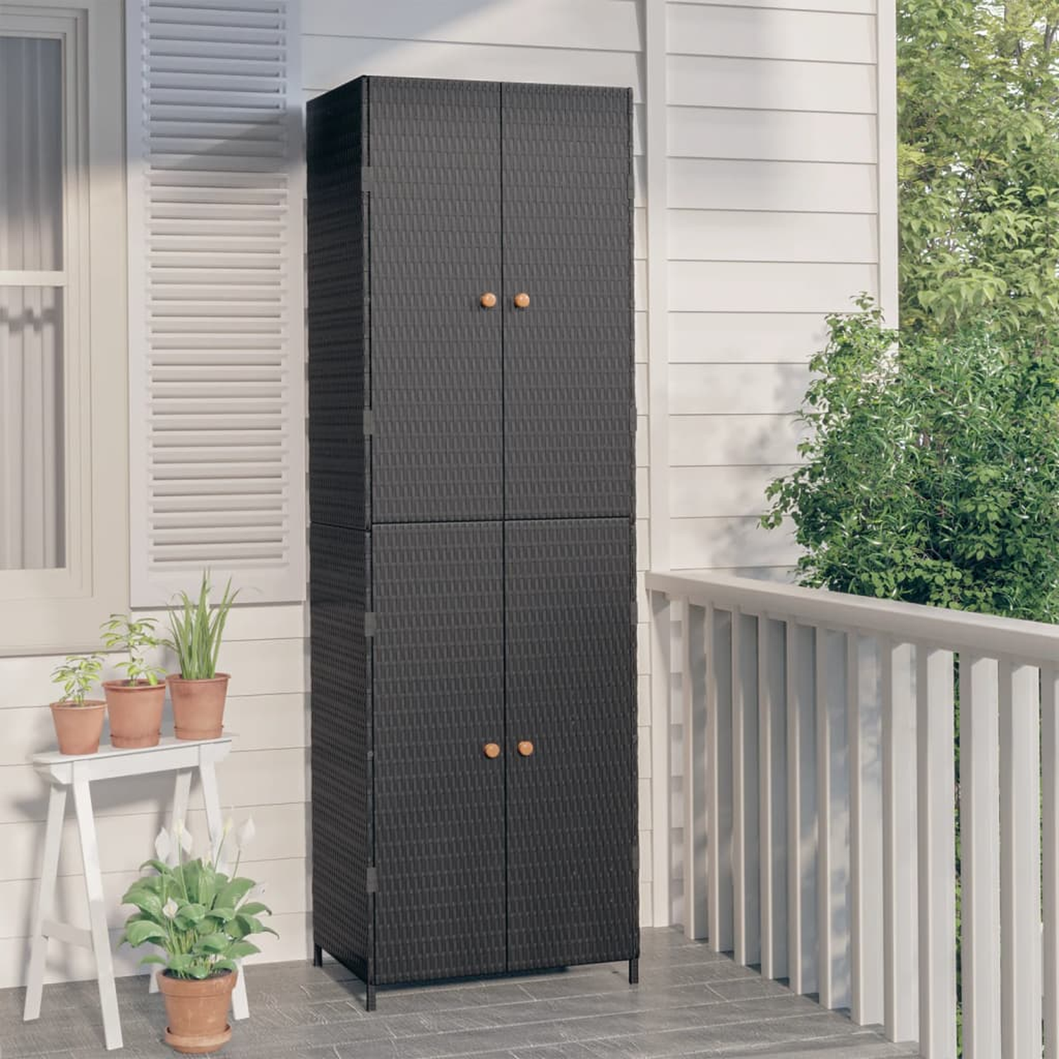 Schwarzer Outdoor-Schrank aus Korbgeflecht mit vier Türen. Auf einer Veranda mit Pflanzen.