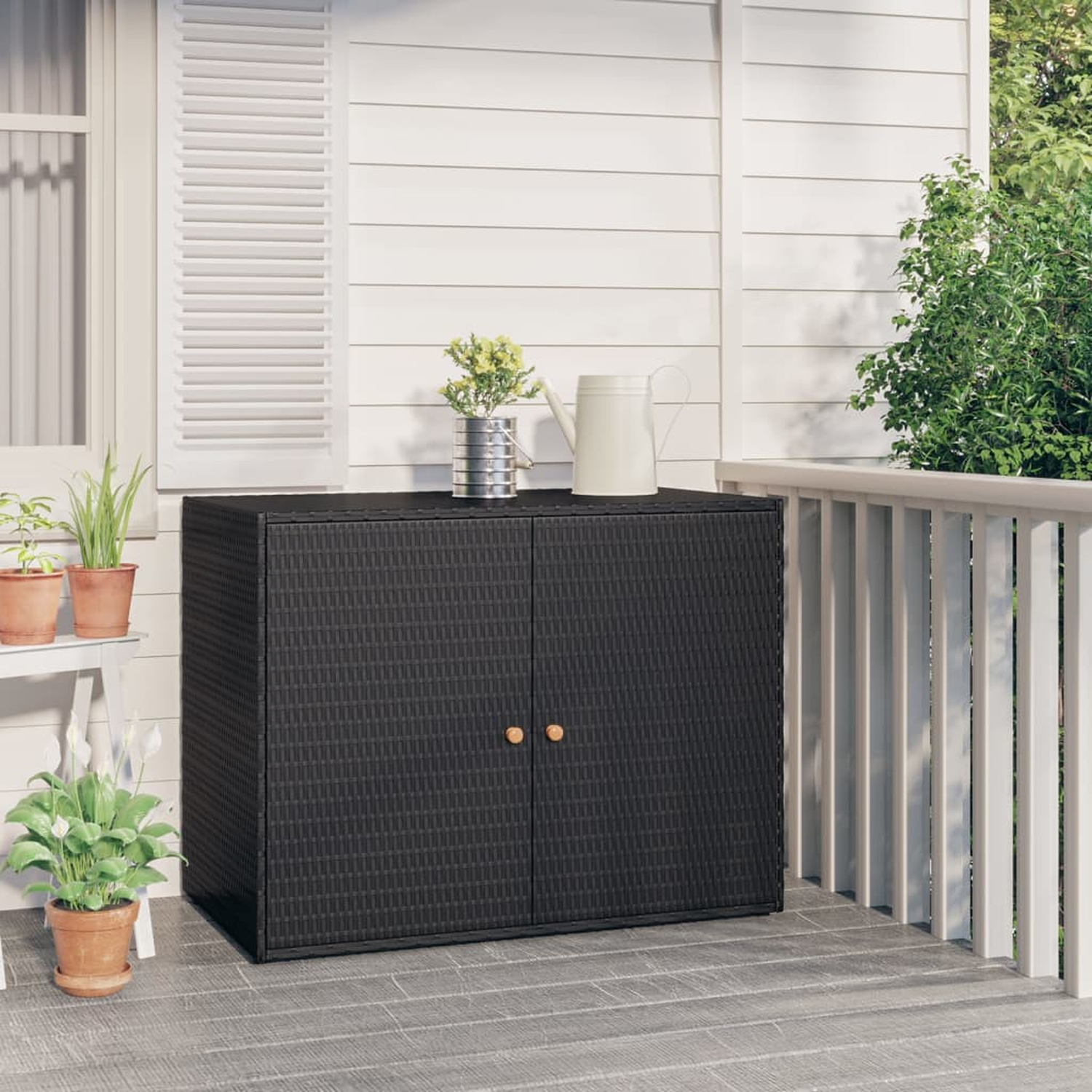 Schwarzer Außenschrank auf einer Veranda, mit zwei Türen und Dekorationsartikeln oben.