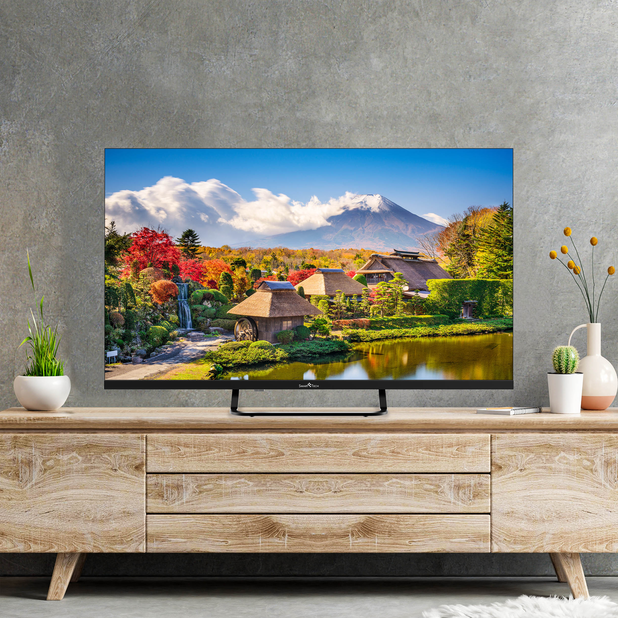 Una TV che mostra un paesaggio giapponese con un lago e montagne. È su un mobile in legno.