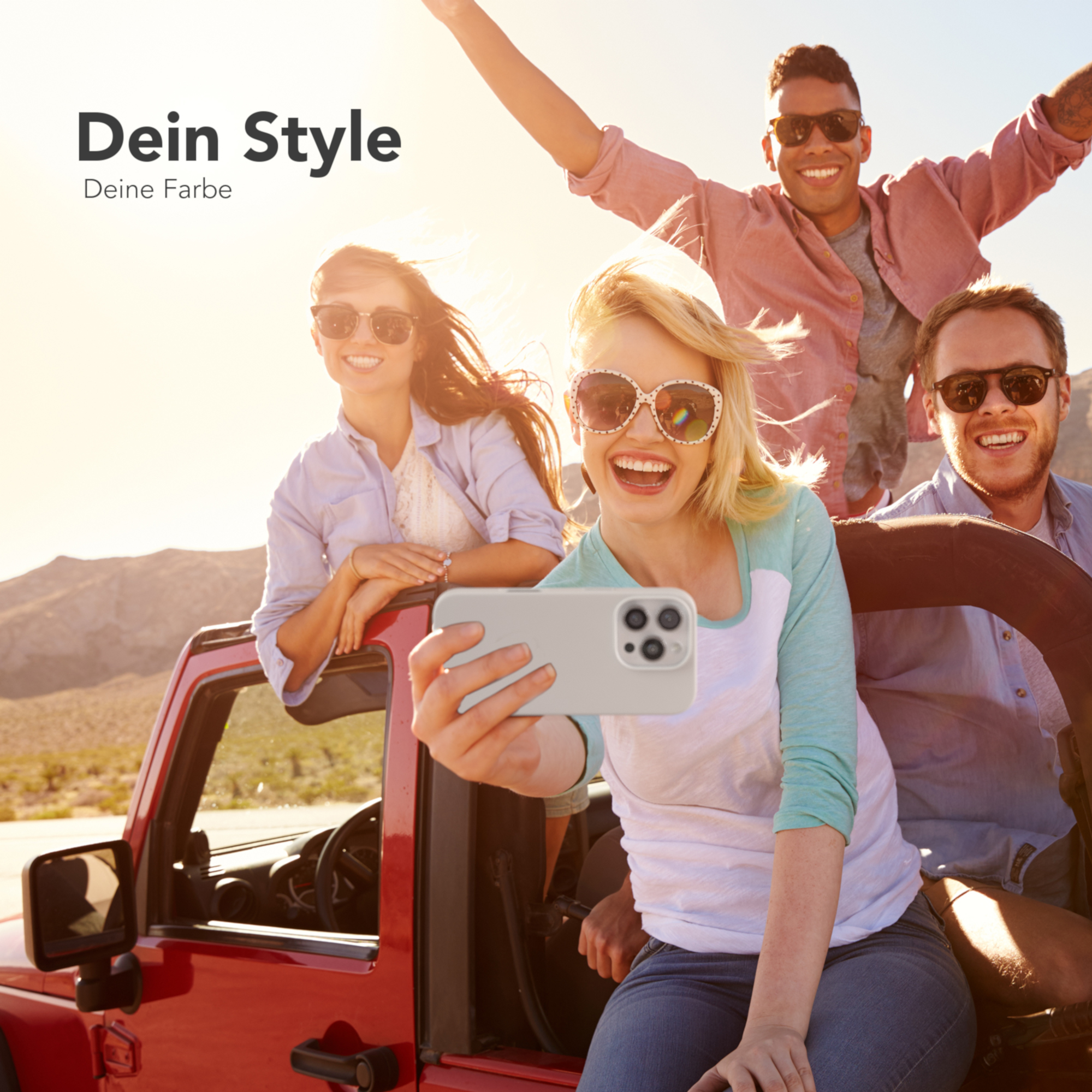 Vier Personen in einem roten Jeep machen ein Selfie. Sonniger Hintergrund. Sonnenbrillen und Lächeln.