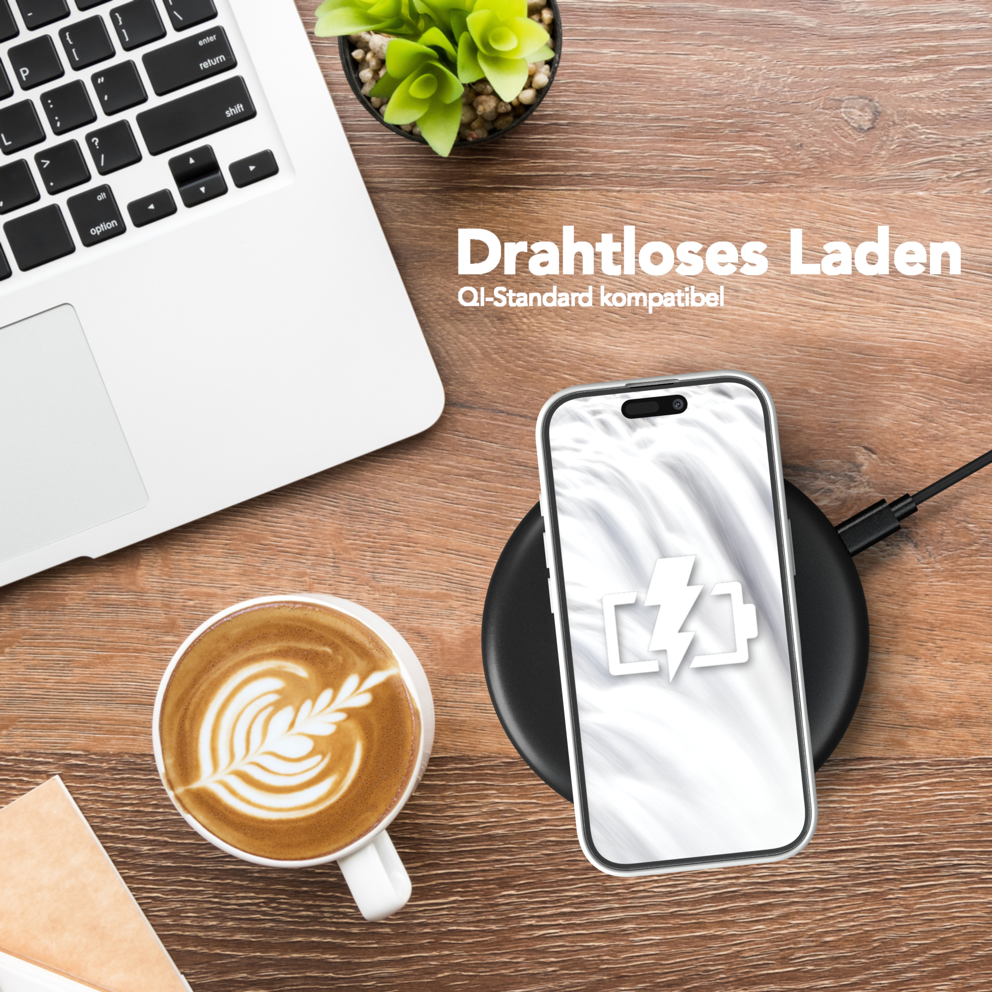 Ein Laptop, eine Tasse Kaffee mit Latte Art und ein Smartphone, das drahtlos geladen wird.