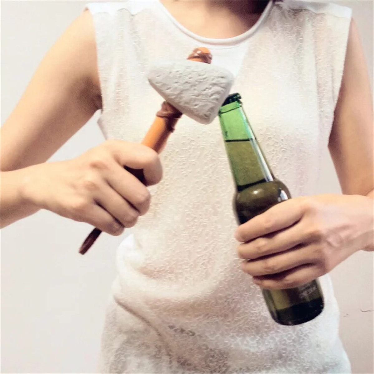 Person öffnet Bier mit einem Flaschenöffner im Steinhammerstil, Bier haltend.