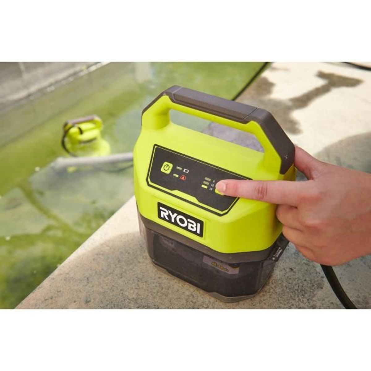 Appareil portable Ryobi vert citron. Un doigt appuie sur un bouton. Un autre appareil visible en arrière-plan.