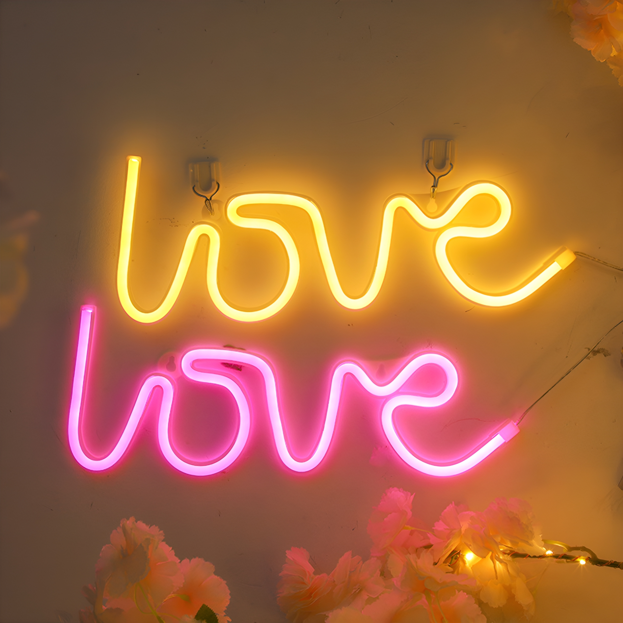 Zwei Neon-Schilder mit dem Wort 'love'. Eines ist gelb, das andere rosa.
