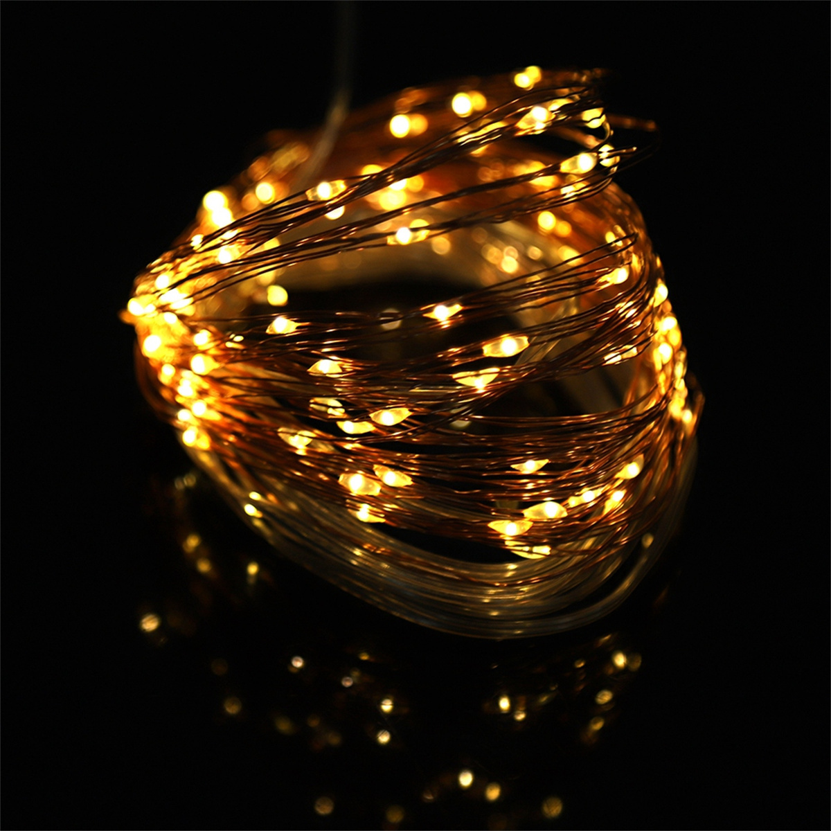 Aufgewickelte Lichterketten. Sie leuchten warm gelb auf schwarzem Hintergrund.