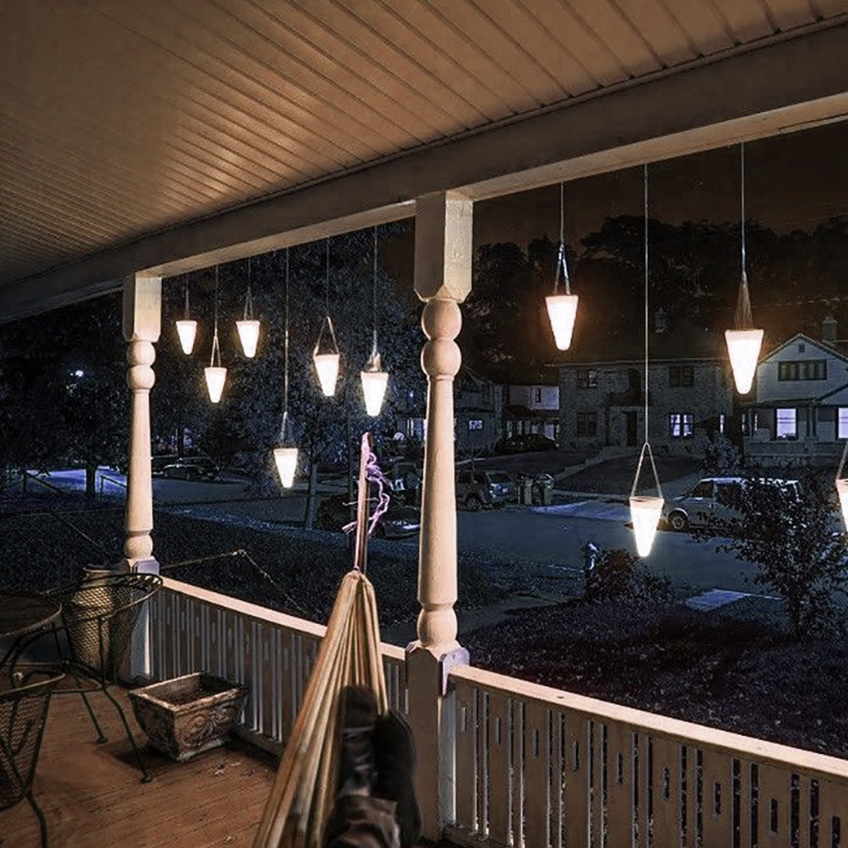 Außenszene bei Nacht mit Hängelampen. Eine Veranda mit Hängematte und Haus im Hintergrund.
