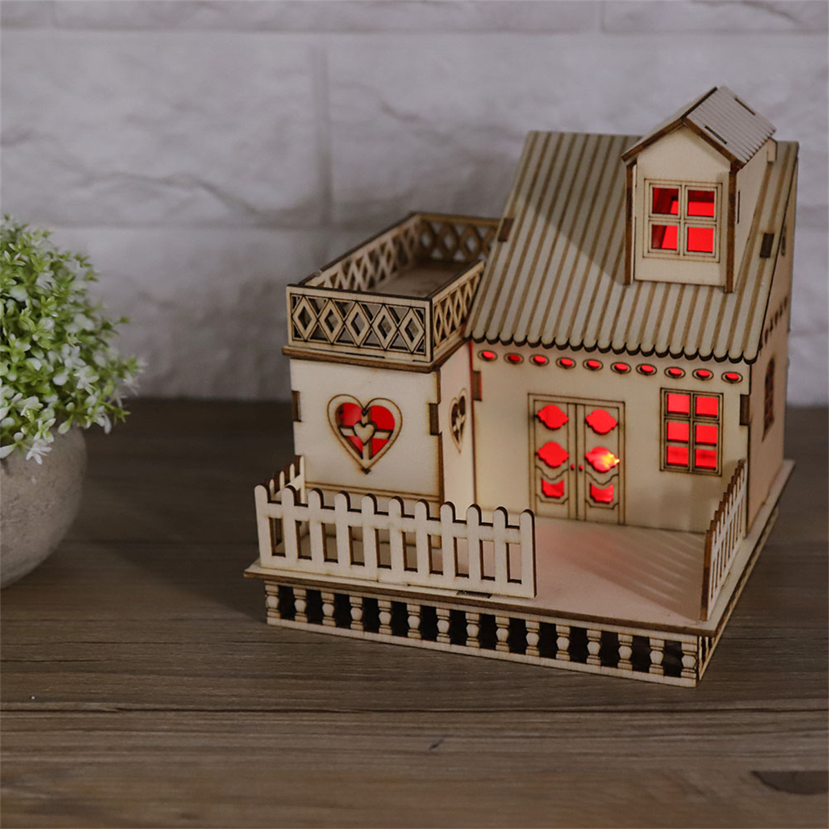 Holzhausmodell mit rot beleuchteten Fenstern und einem Herzdesign.