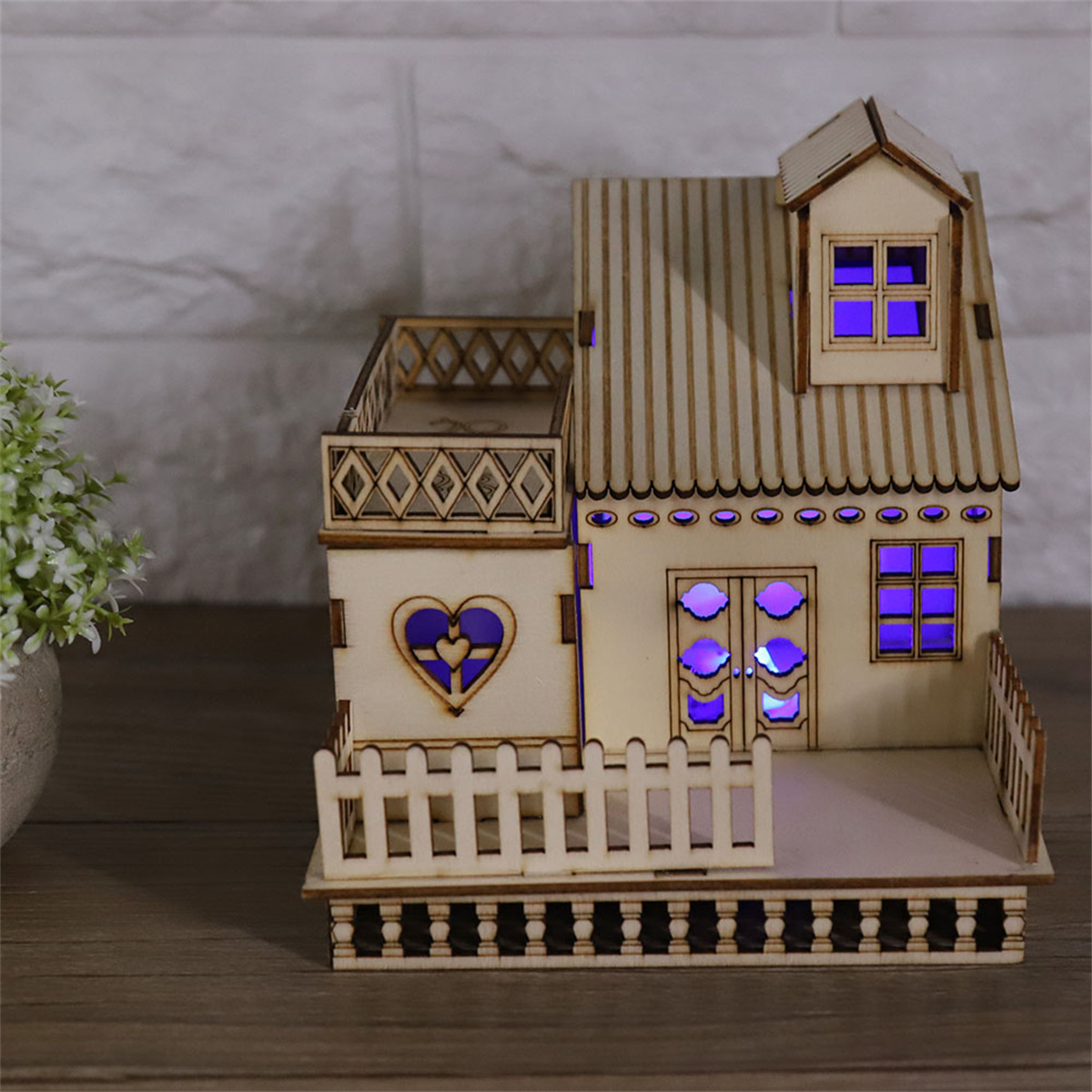 Ein kleines Holzhausmodell mit Lichtern, Balkon und herzförmigem Ausschnitt.