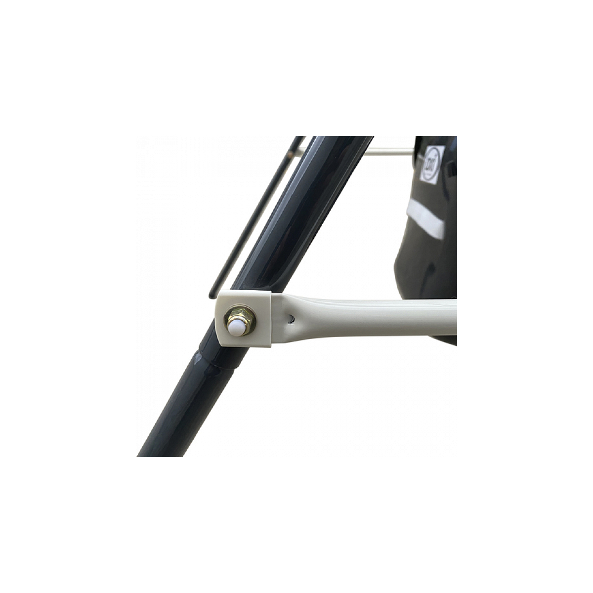 Nahaufnahme eines metallischen Schaukelgestellgelenks. Ein Bolzen verbindet zwei dunkelgraue Stangen mit einem weißen Arm.