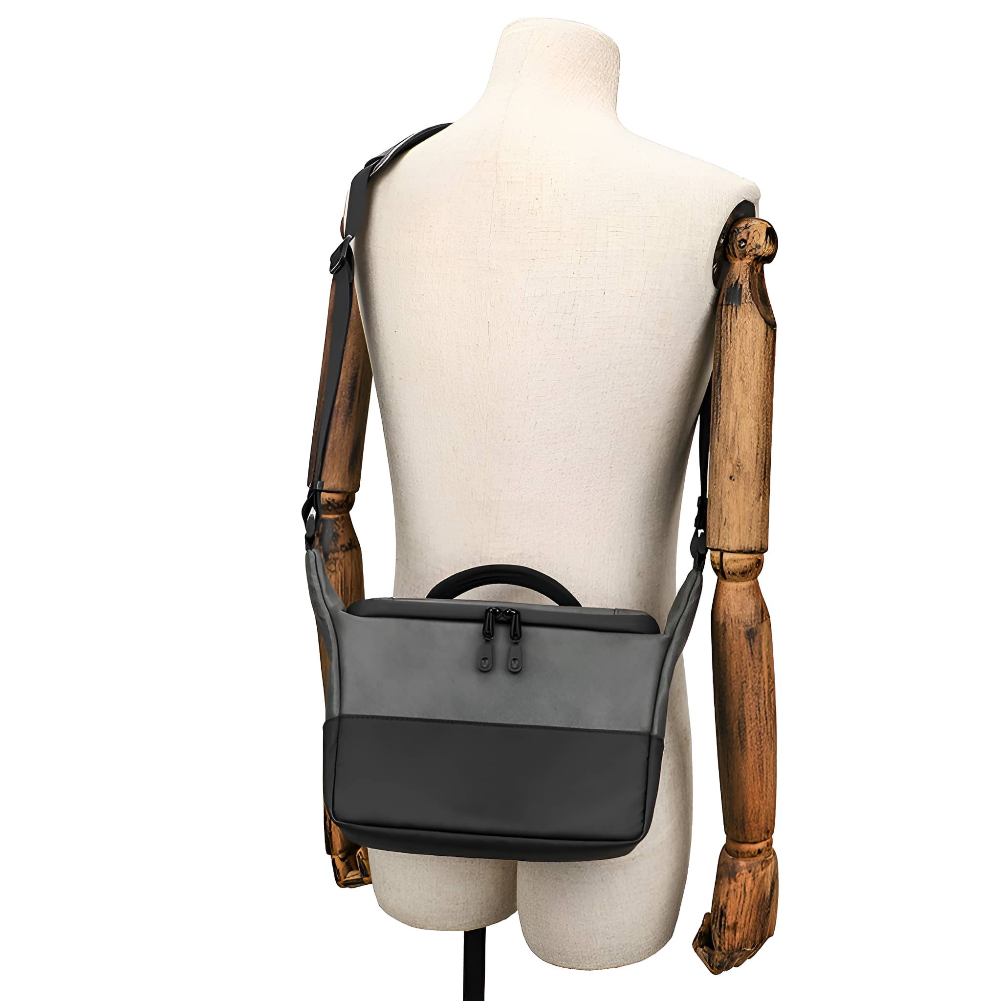 Eine Schaufensterpuppe mit einer grau-schwarzen Umhängetasche. Tasche mit Griff und Gurt.