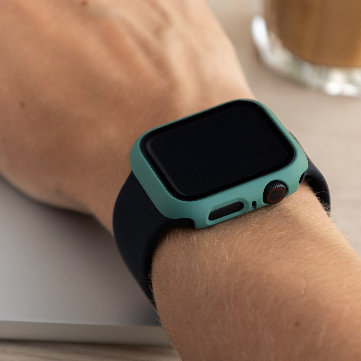 A person's wrist with a green watch and a black case. The watch shows the time.