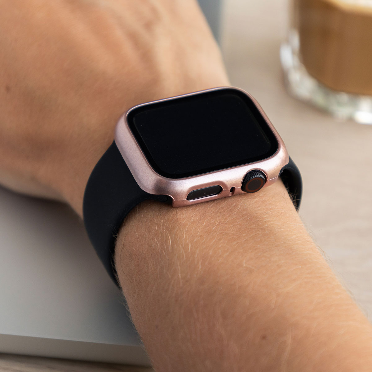 A person's wrist wearing a black watch with a rose gold case.