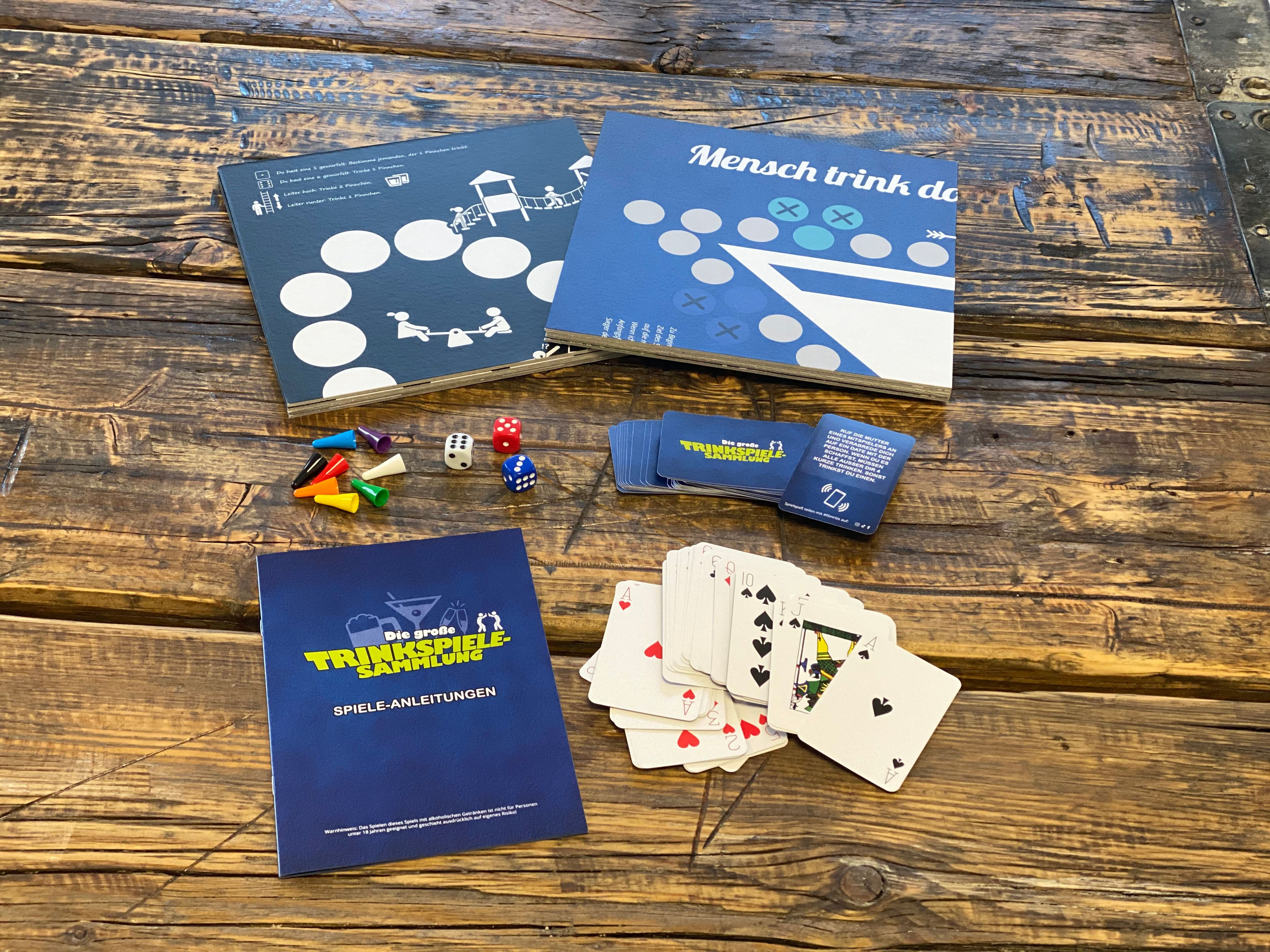 Brettspiel-Setup auf einem Holztisch: Spielbretter, Karten, Würfel, Spielfiguren und Anweisungen.