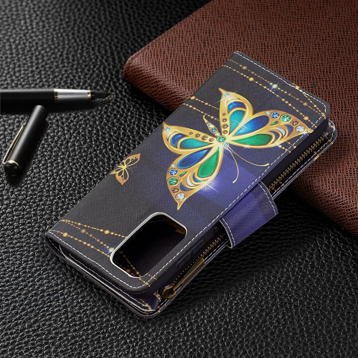 Schwarze Handyhülle mit Schmetterlingsdesign, ein Stift und eine braune Geldbörse.