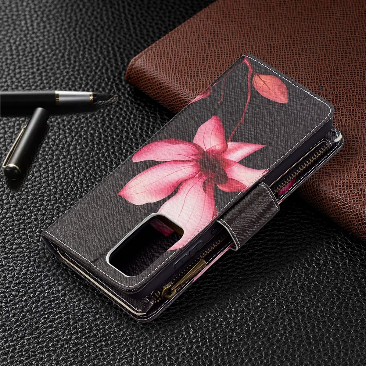Handyhülle mit floralem Design. Stift und Notizbuch auf Lederoberfläche.