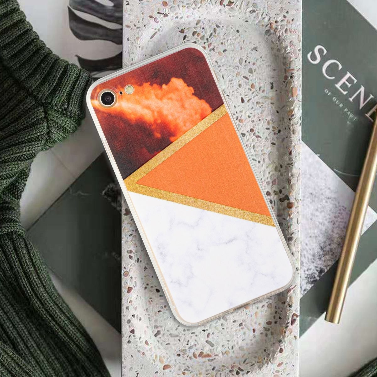 Telefon mit orange-weißem Design. Auf einem Tablett mit Stift und Zeitschrift.