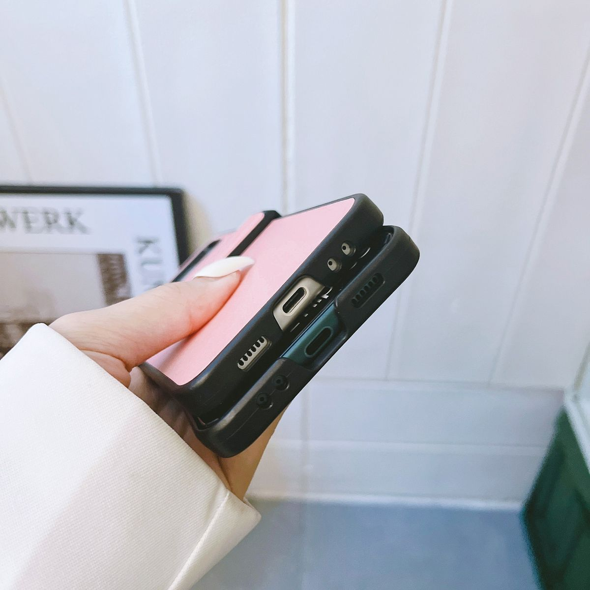 Hand hält eine rosa Handyhülle mit schwarzem Rahmen. Das Telefon ist zusammengeklappt.