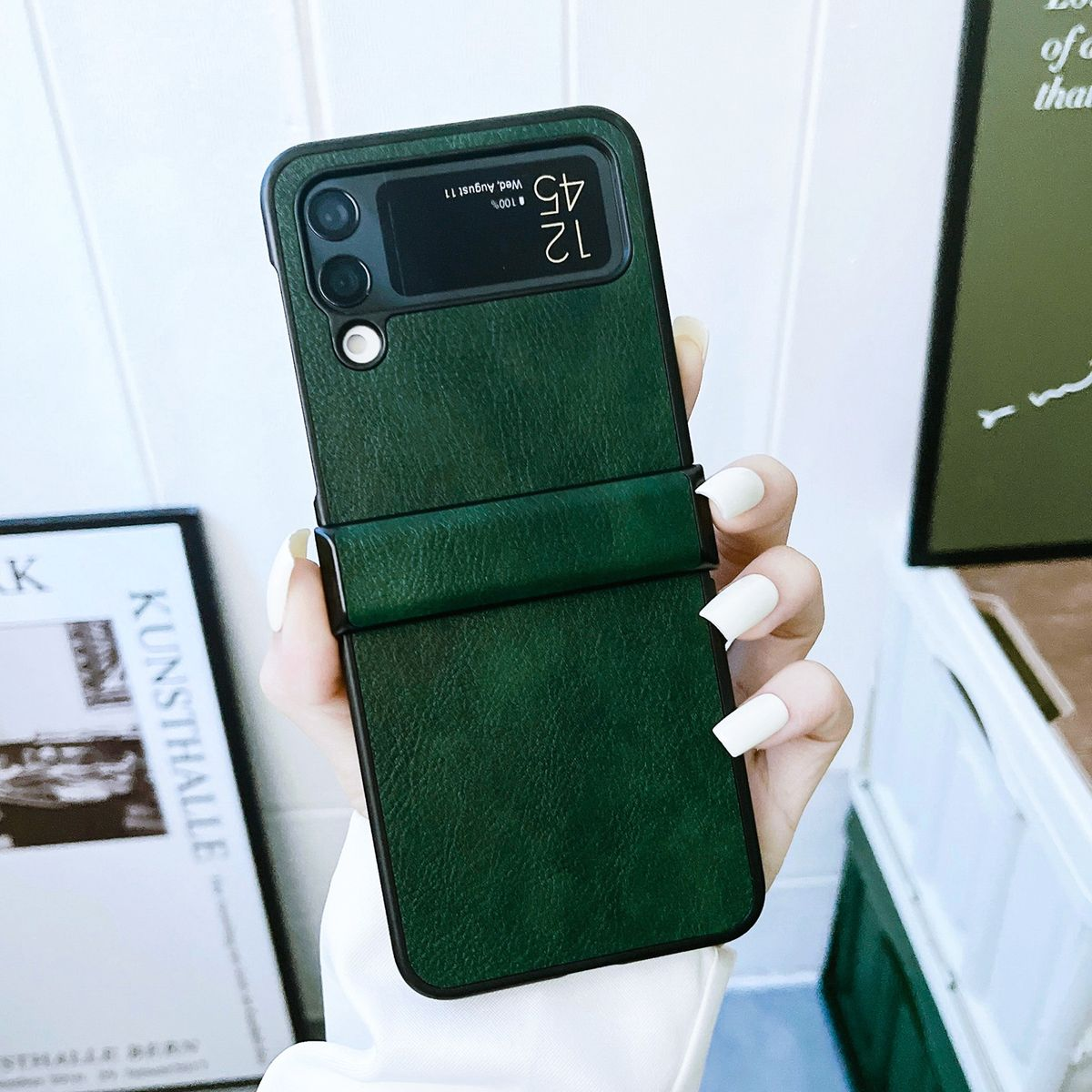 Grüne Handyhülle mit Riemen, Telefon liegt seitlich, vor weißem Hintergrund.