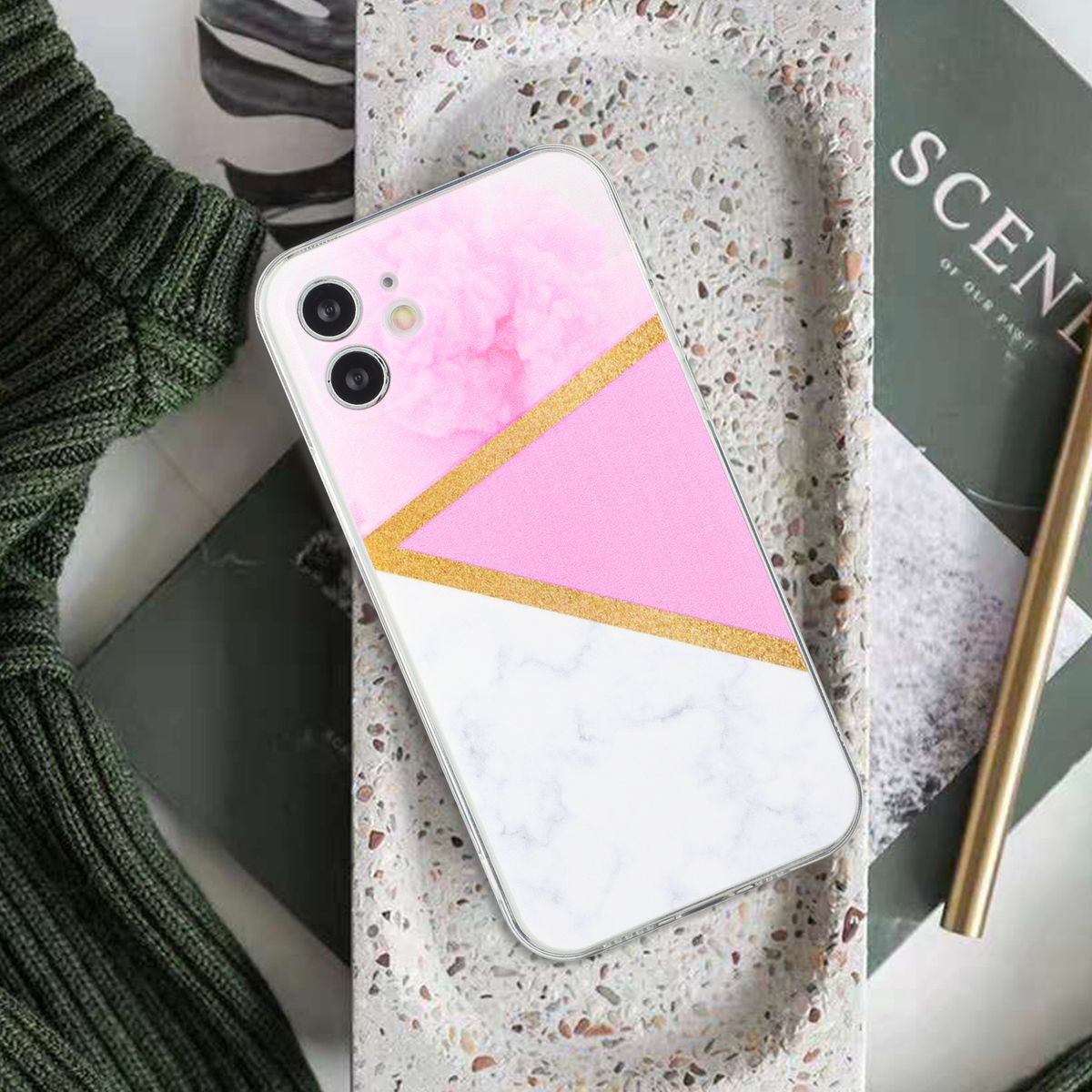 Telefon mit rosa und weißer Hülle mit goldenen Akzenten, liegt auf einem Tablett.