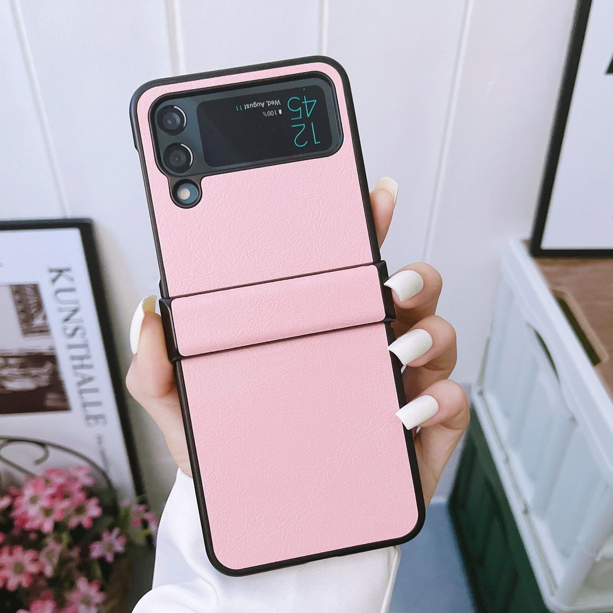 Rosa Handyhülle mit Telefon, gehalten von Hand mit lackierten Nägeln.