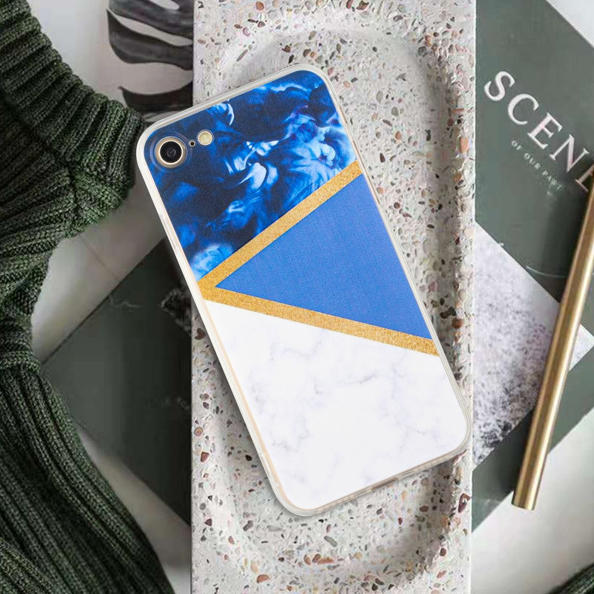 Handyhülle mit blauem, weißem und goldenem Design. Sie liegt auf einem Steintablett mit einer Zeitschrift und einem goldenen Stift.