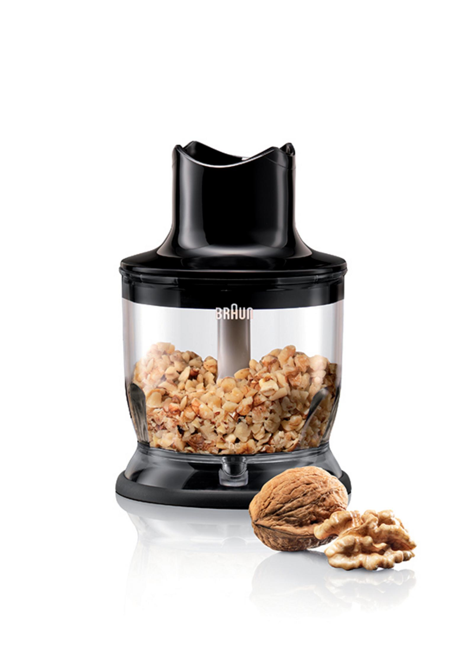 Licuadora negra con nueces dentro y nueces al lado.