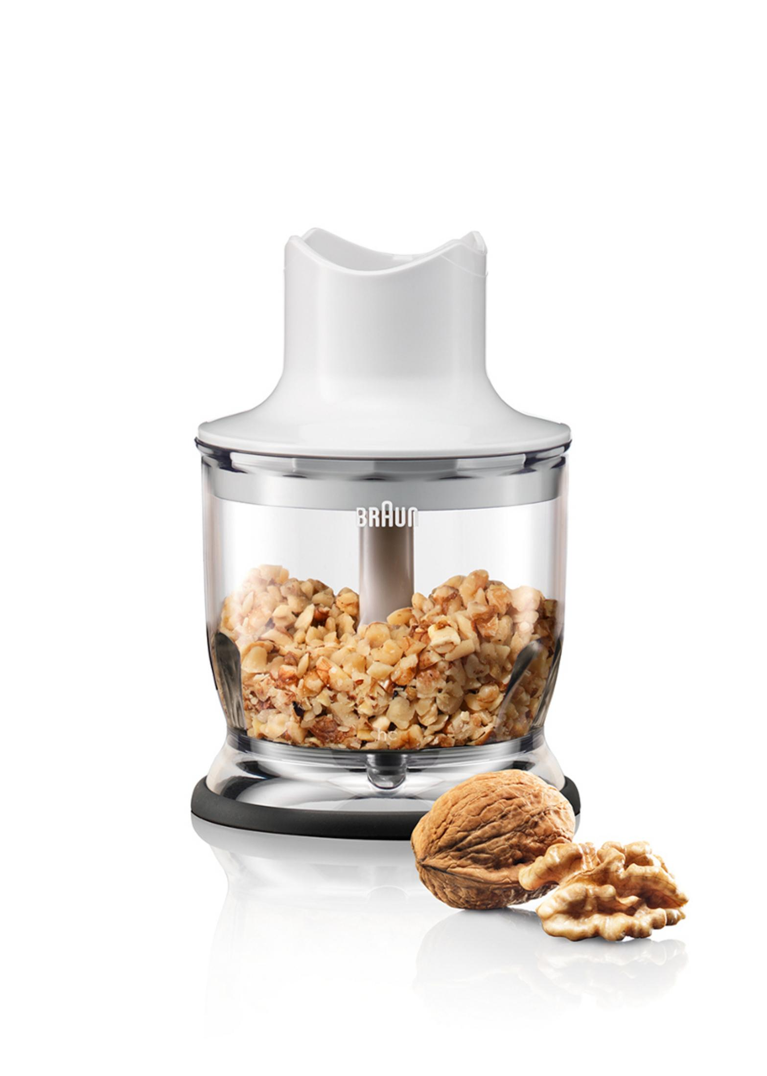 Licuadora blanca y transparente con nueces dentro. Nueces junto a la licuadora.