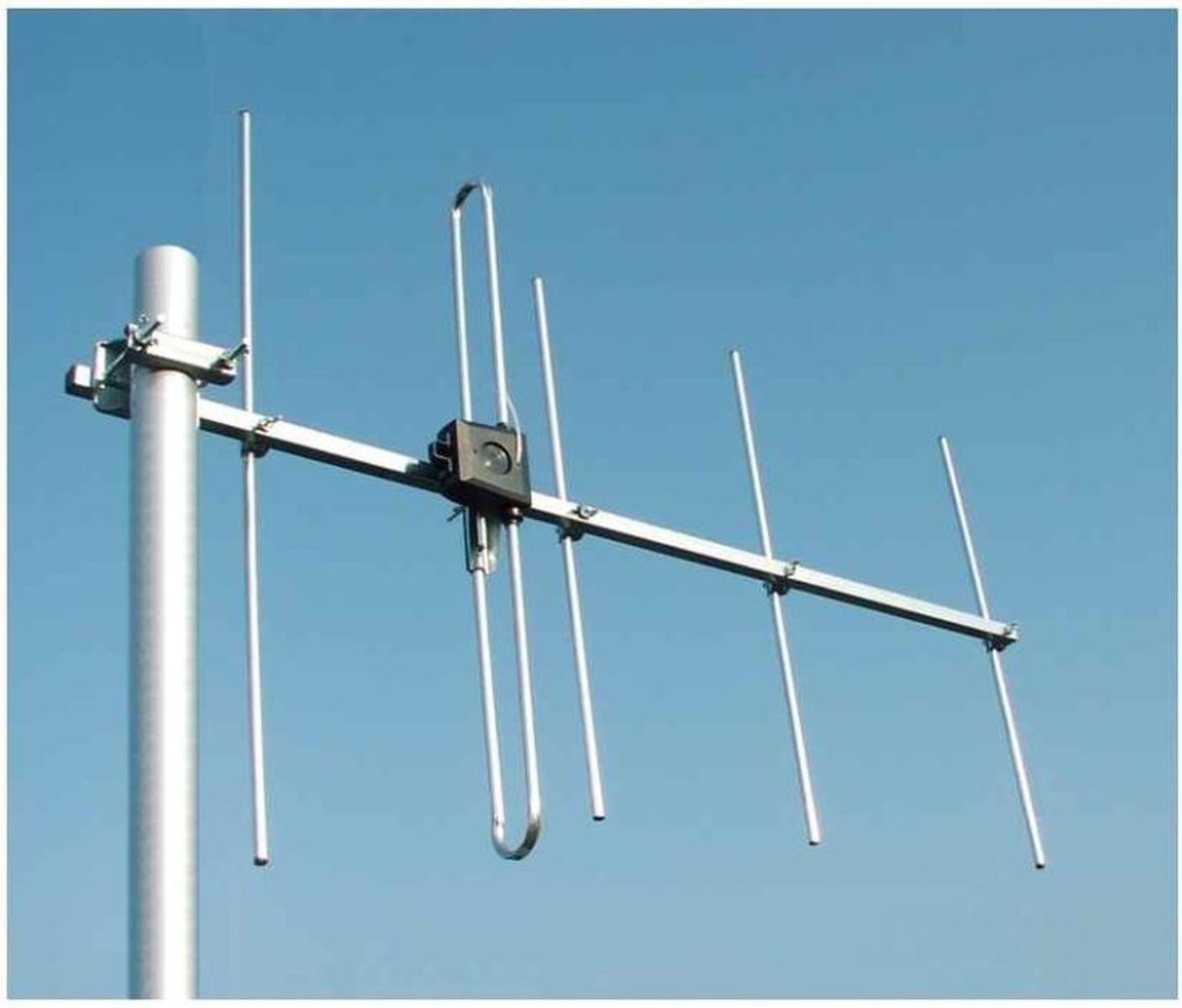 Antenne an einem Mast vor blauem Himmel. Die Antenne ist silberfarben, mit mehreren Armen.