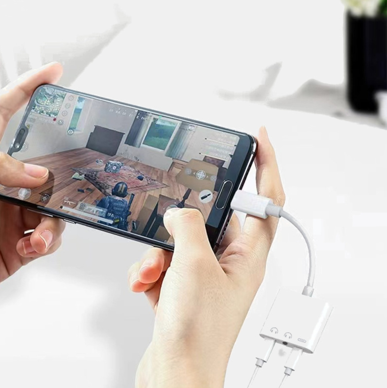 Hände halten ein Telefon mit Adapter, spielen ein Spiel. Weißer Hintergrund.