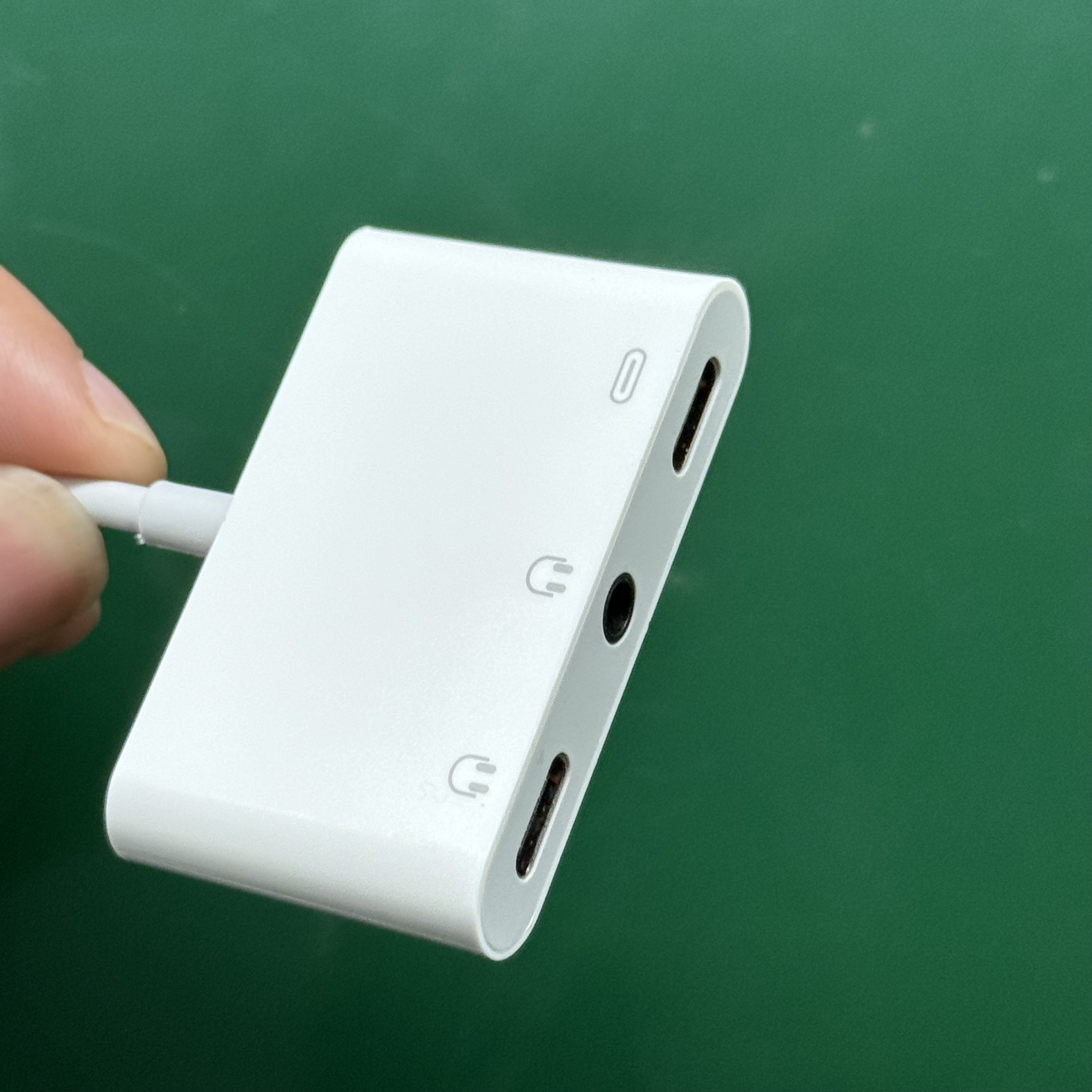 Weißer Adapter mit USB-C- und Kopfhöreranschlüssen auf grünem Hintergrund.