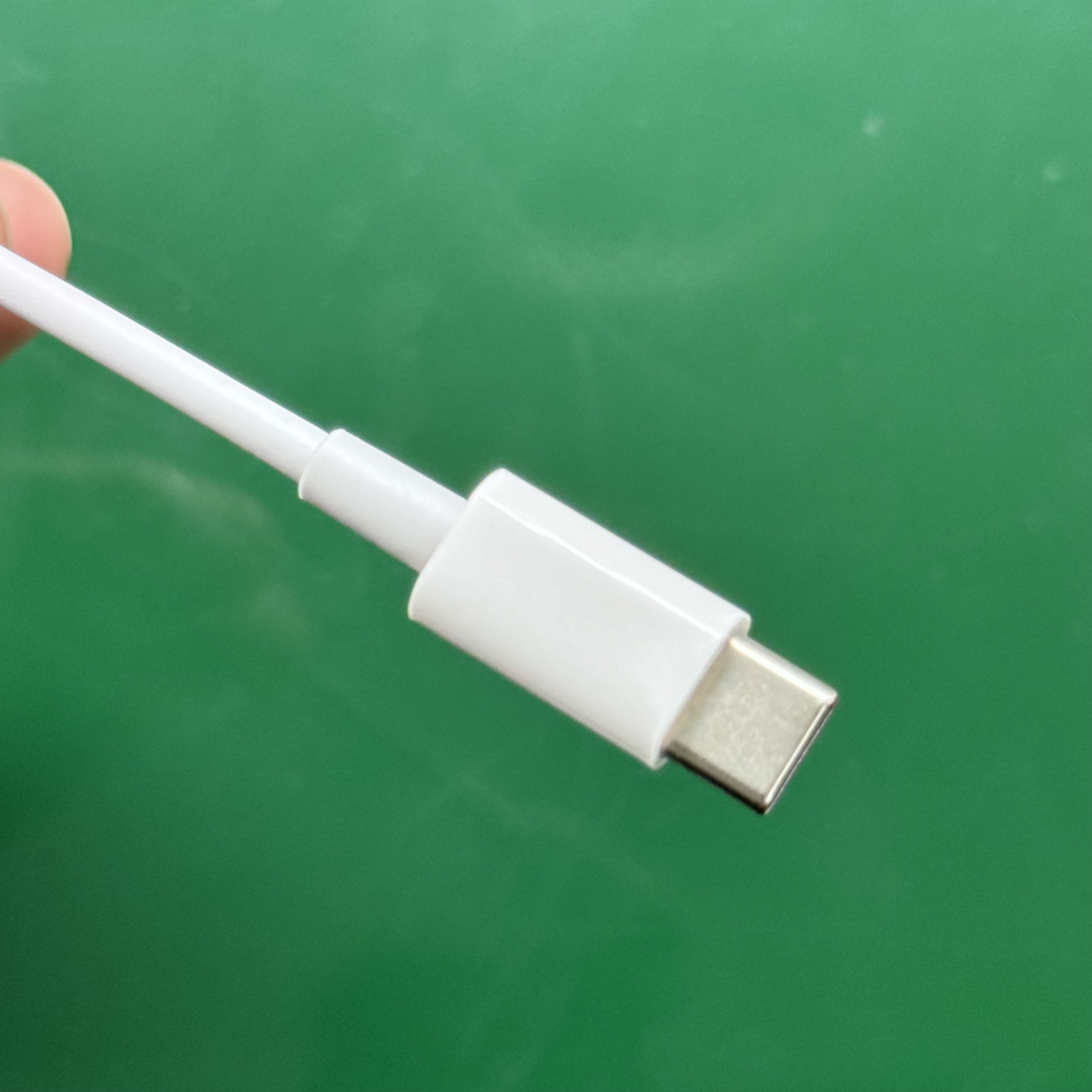 Weißes USB-C-Kabel mit weißem Stecker. Grüner Hintergrund.