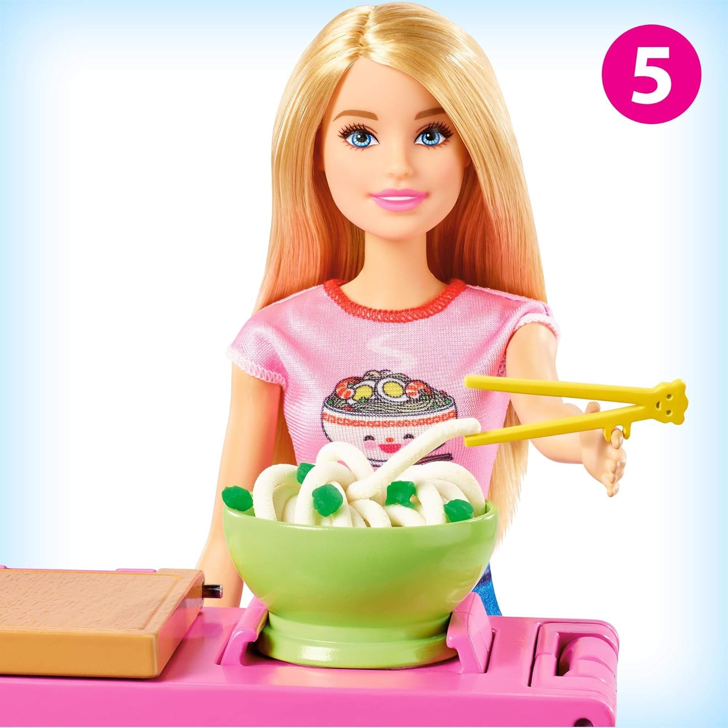 Bambola Barbie con top rosa e ciotola di noodles. Bacchette in mano. Numero 5 visibile.