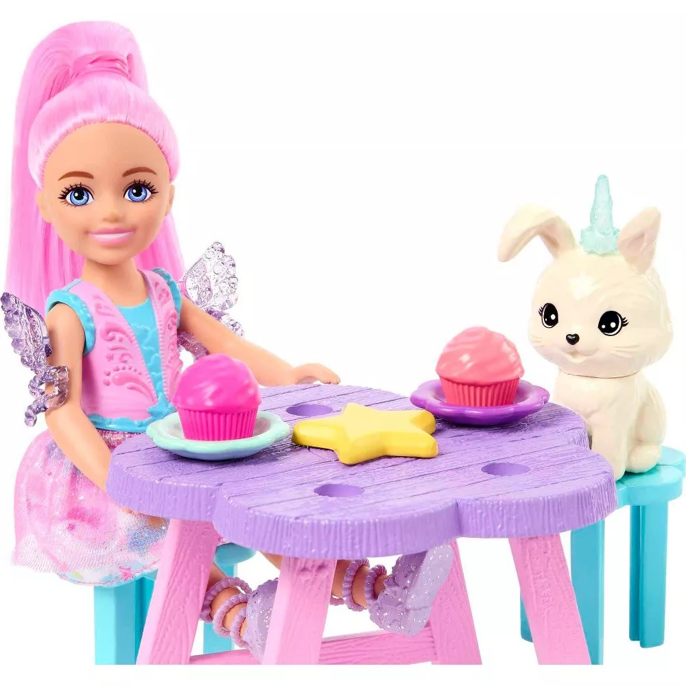 Bambola e coniglietto a un tavolo viola. Cupcake e stella. Bambola con i capelli rosa. Sfondo bianco.
