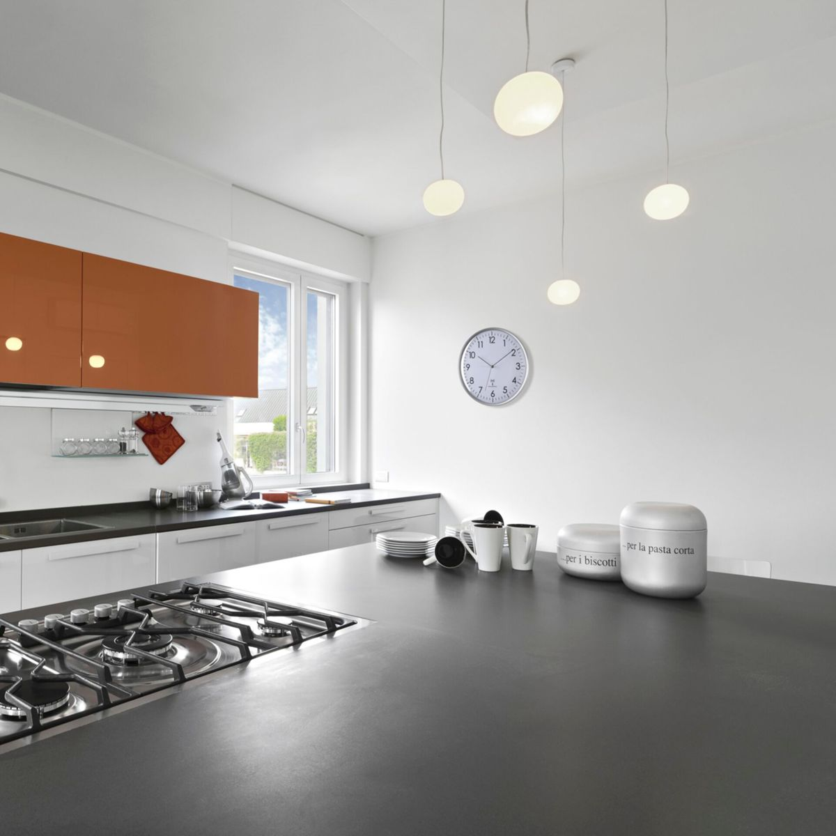 Kuchnia z białymi ścianami i czarnym blatem, światła wiszące nad.