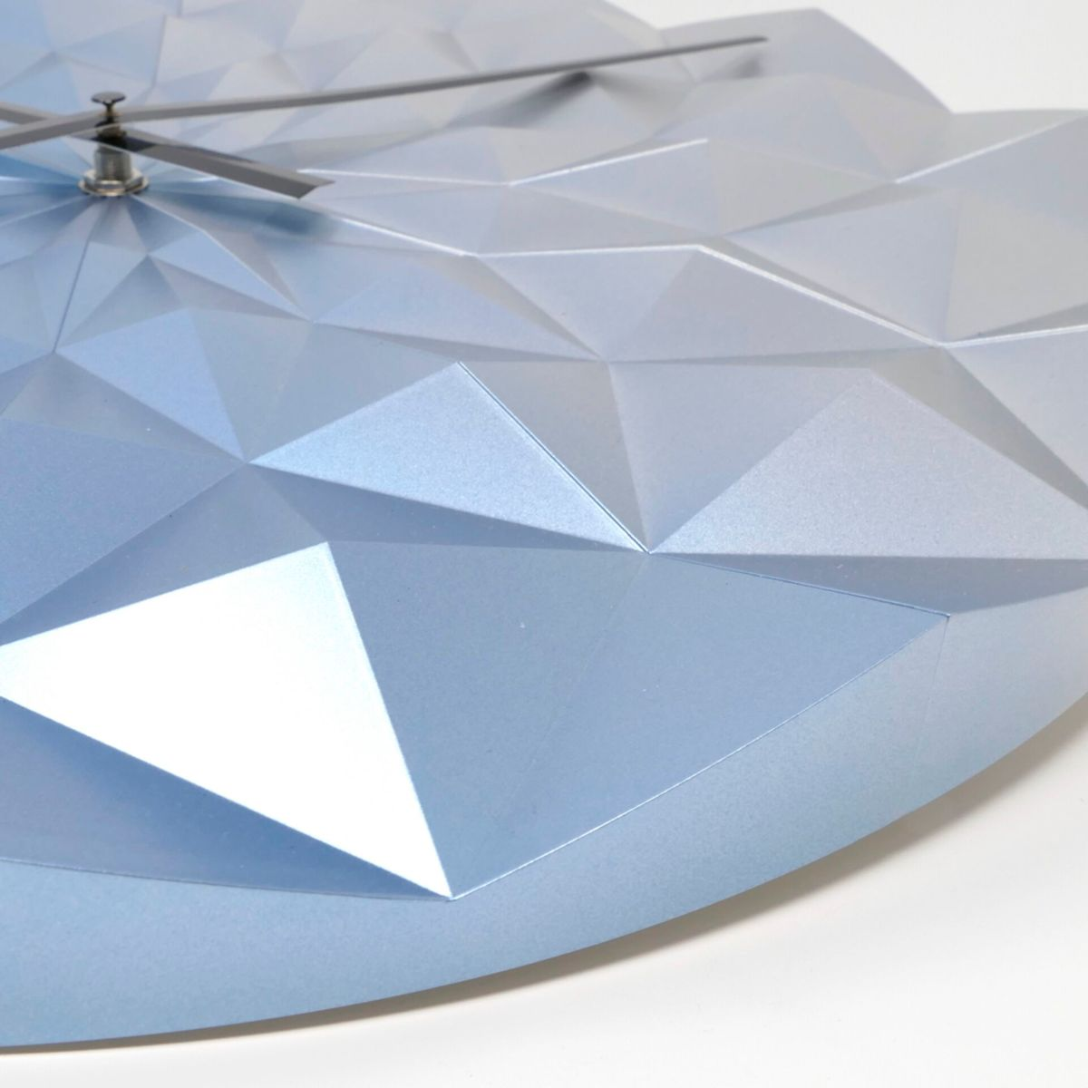 Eine hellblaue Uhr mit geometrischem Muster vor weißem Hintergrund, die Zeit anzeigend.