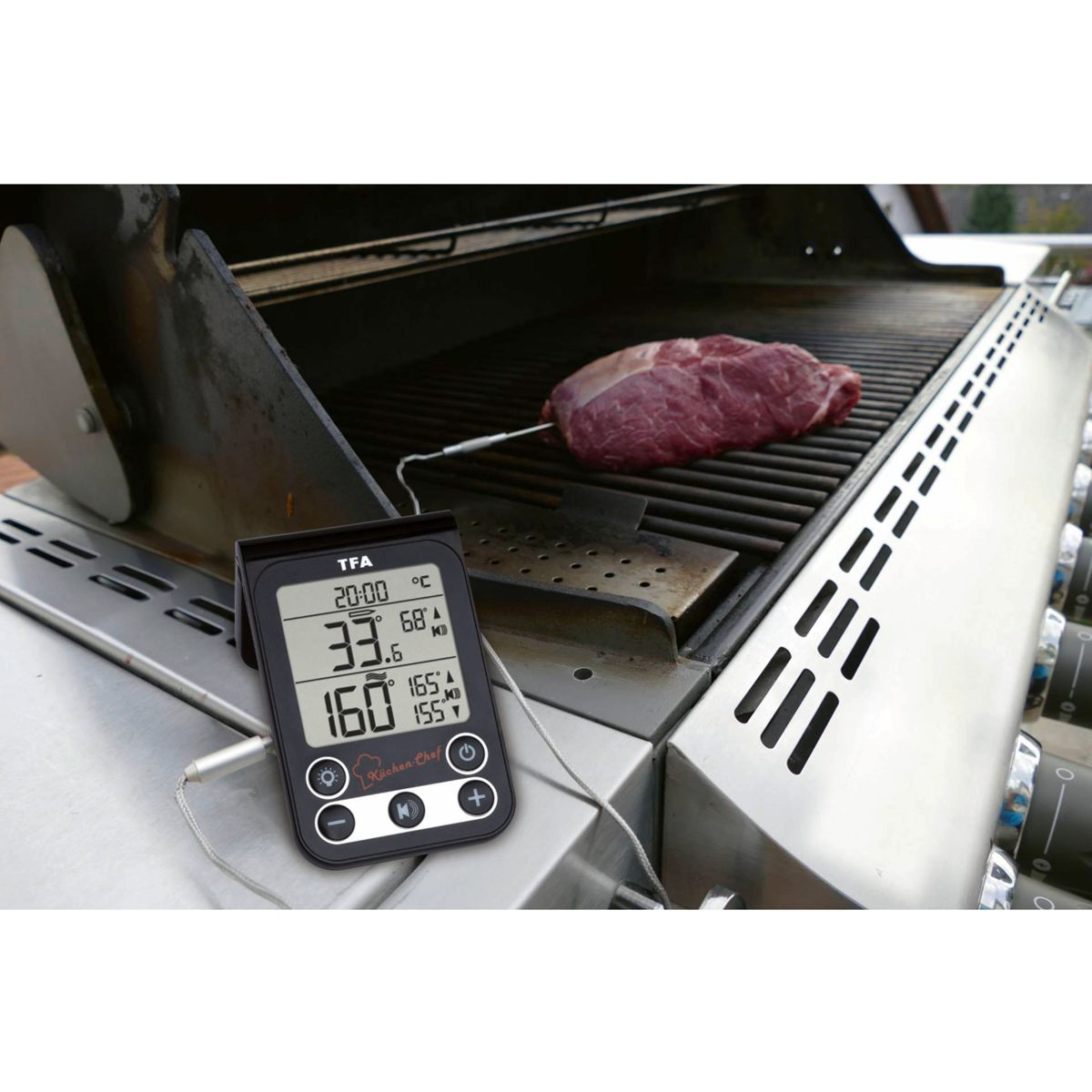 Ein digitales Thermometer befindet sich neben einem Steak auf einem Grill. Der Bildschirm zeigt Temperaturmesswerte in Celsius und Fahrenheit.