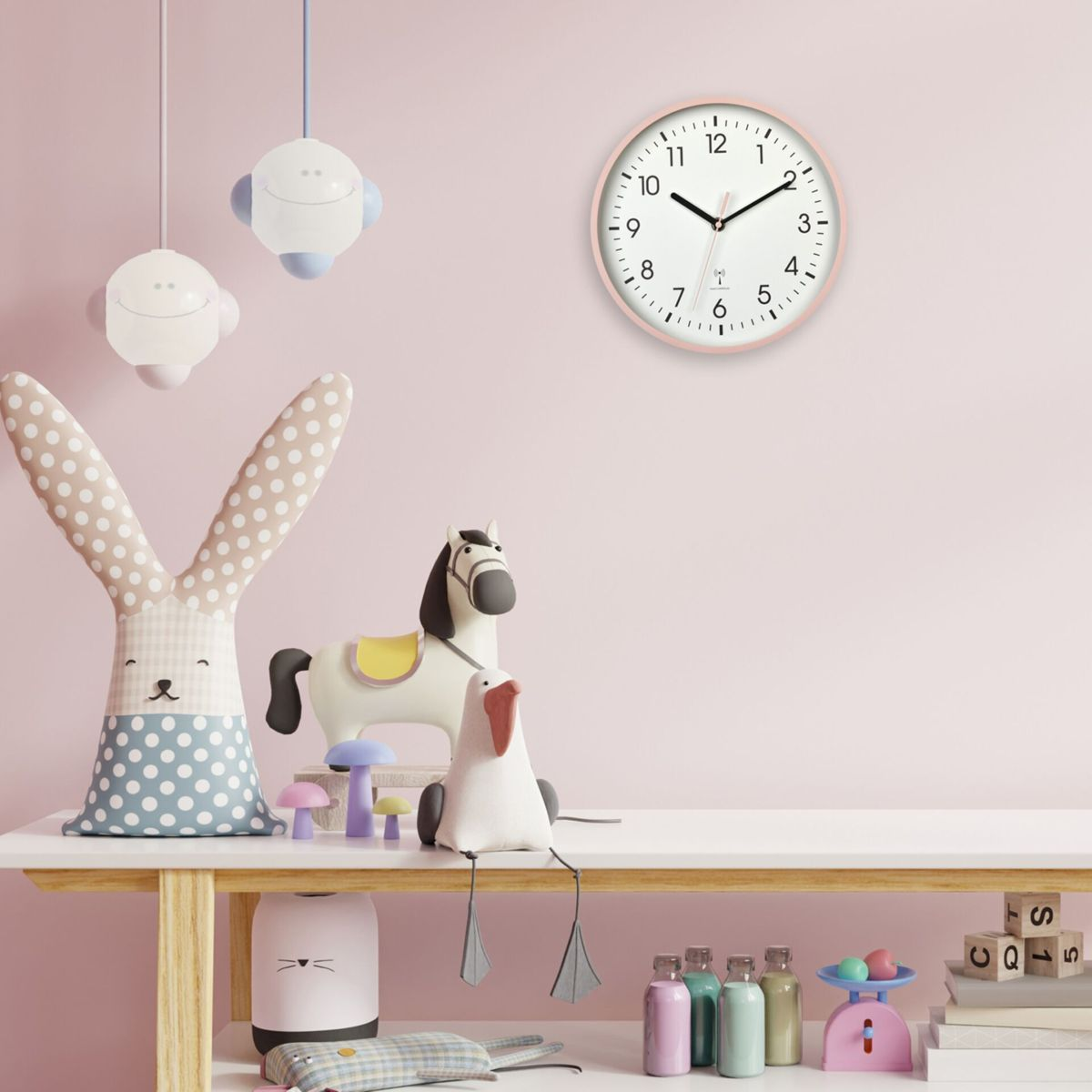 Chambre rose avec horloge, jouets. Table blanche avec jouets. Rose, bleu, blanc et jaune.