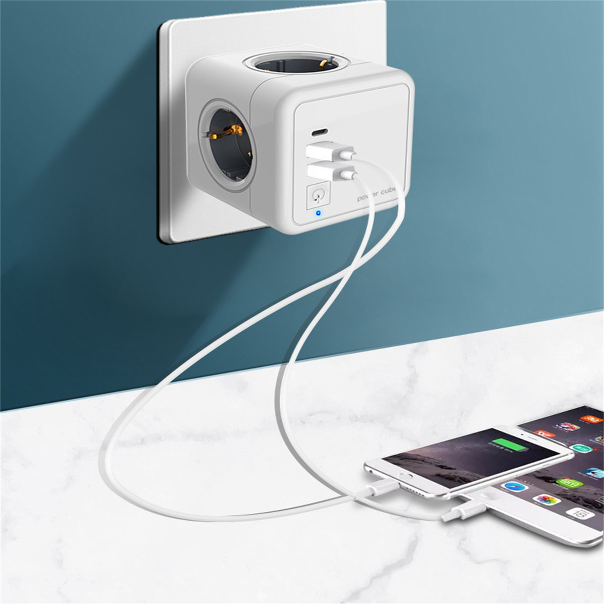 Weißer Power Cube mit mehreren Steckdosen und USB-Anschlüssen. Auf einem Tisch mit Telefonen.