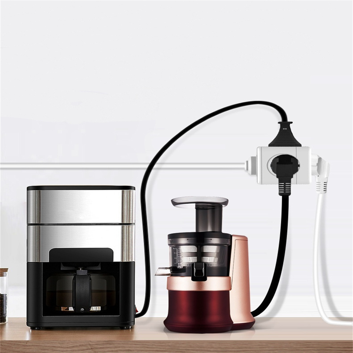 Kaffeemaschine und Entsafter sind an eine Steckdosenleiste angeschlossen. Eine weiße Wand ist dahinter.