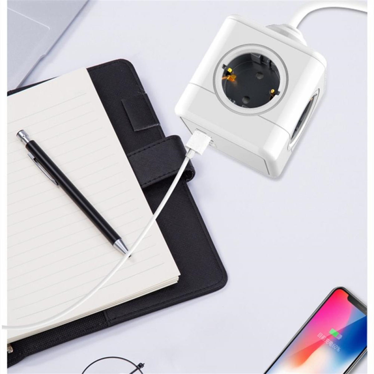 Weiße Steckdosenleiste, verbunden mit Notebook, Stift und ladendem Handy auf weißer Oberfläche.