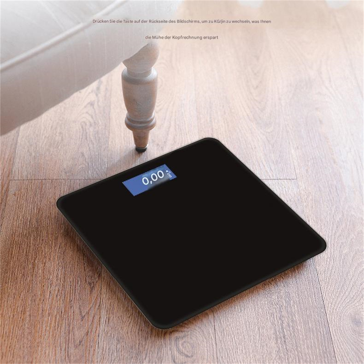 Eine schwarze Digitalwaage auf einem Holzboden zeigt auf ihrem Display "0,00" an.