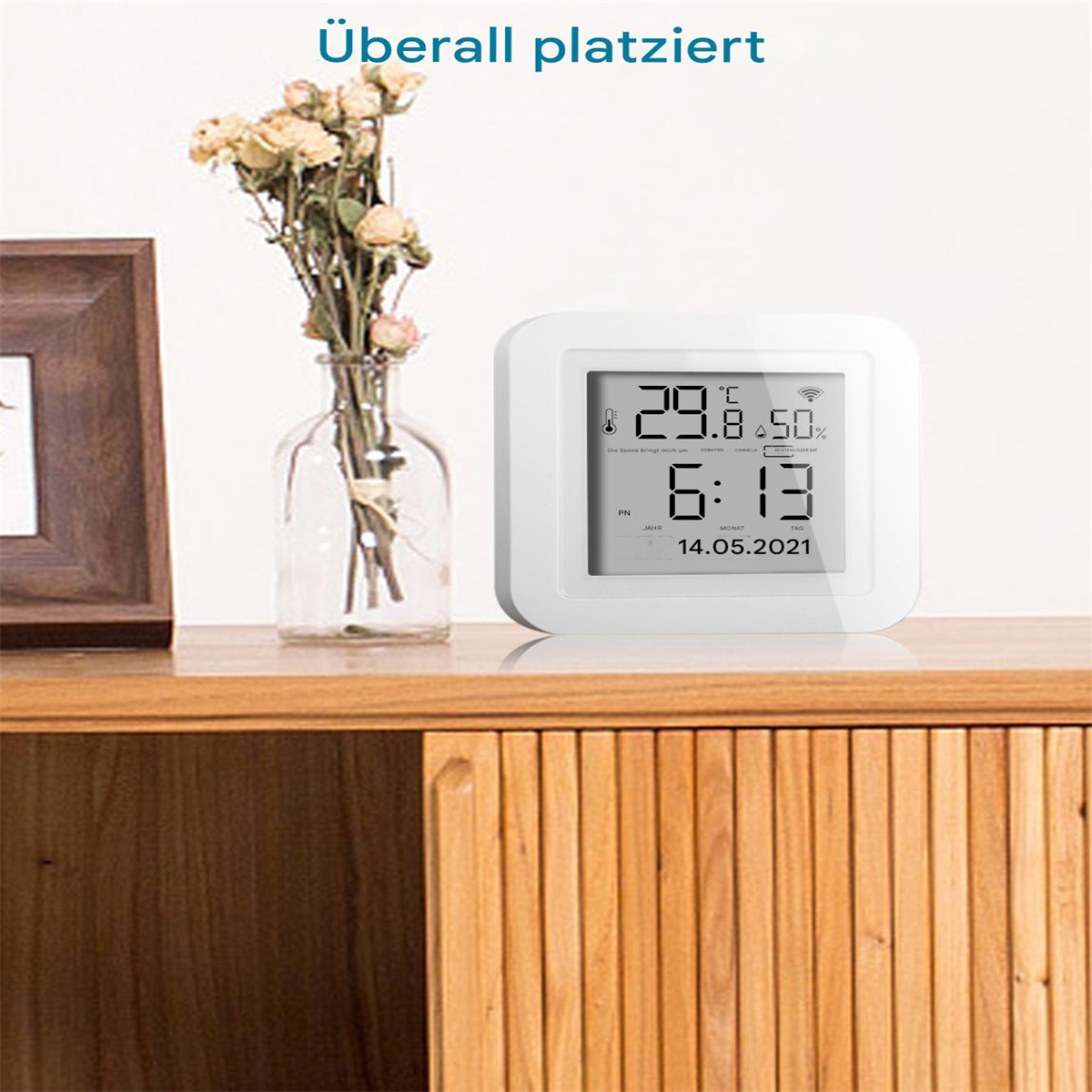 Weiße Digitaluhr, die Temperatur und Uhrzeit auf Holzoberfläche anzeigt.